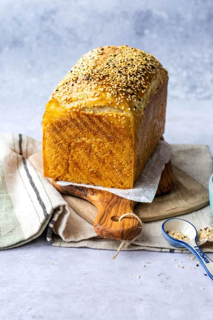 Προζυμένιο ψωμί σε φόρμα πασπαλισμένο με σουσάμι, σε ξύλινη επιφάνεια