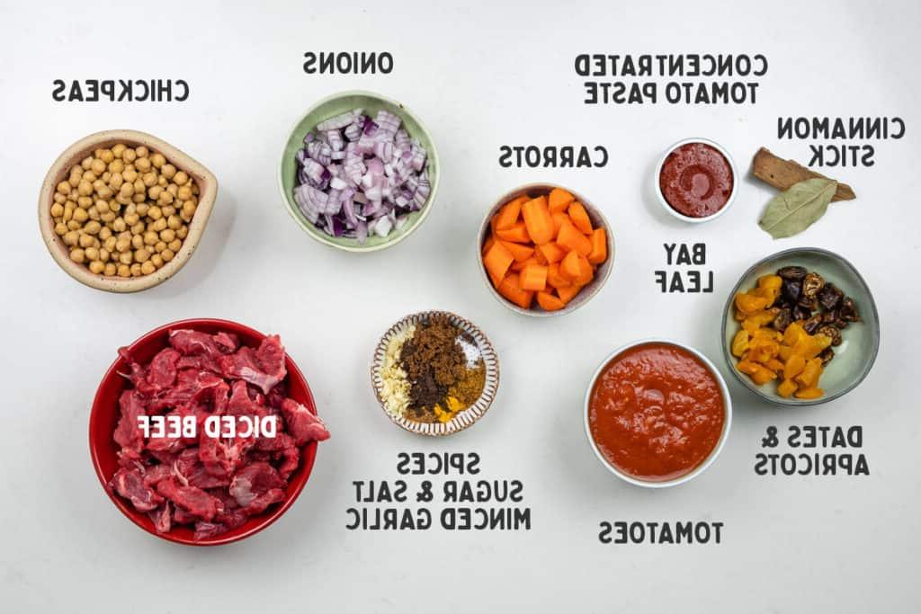 Υλικά για μοσχαρίσιο ταζίν σε λευκό φόντο με λεζάντες.