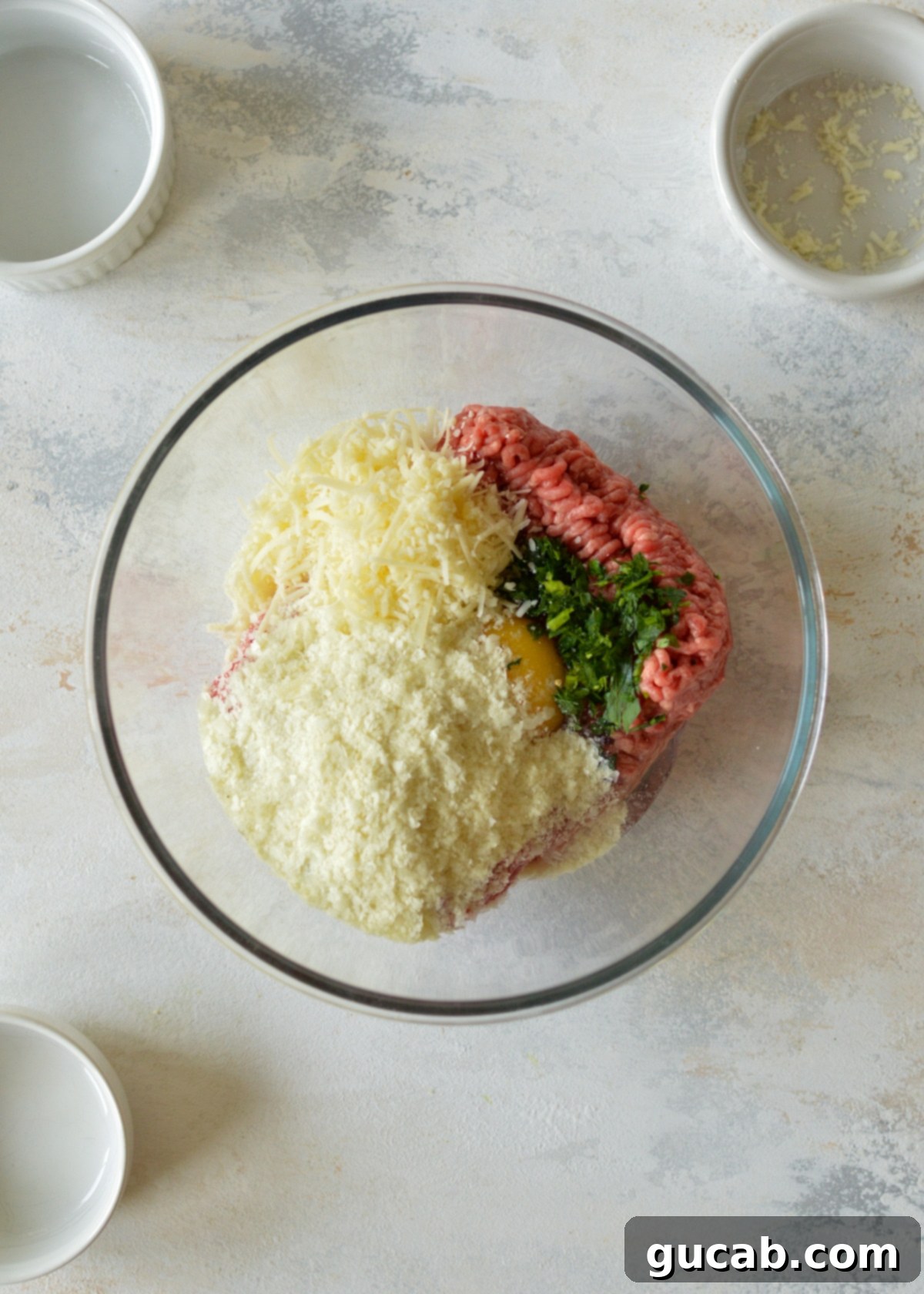 a bowl of ground beef, parmesan, potato flakes, egg, and parsley