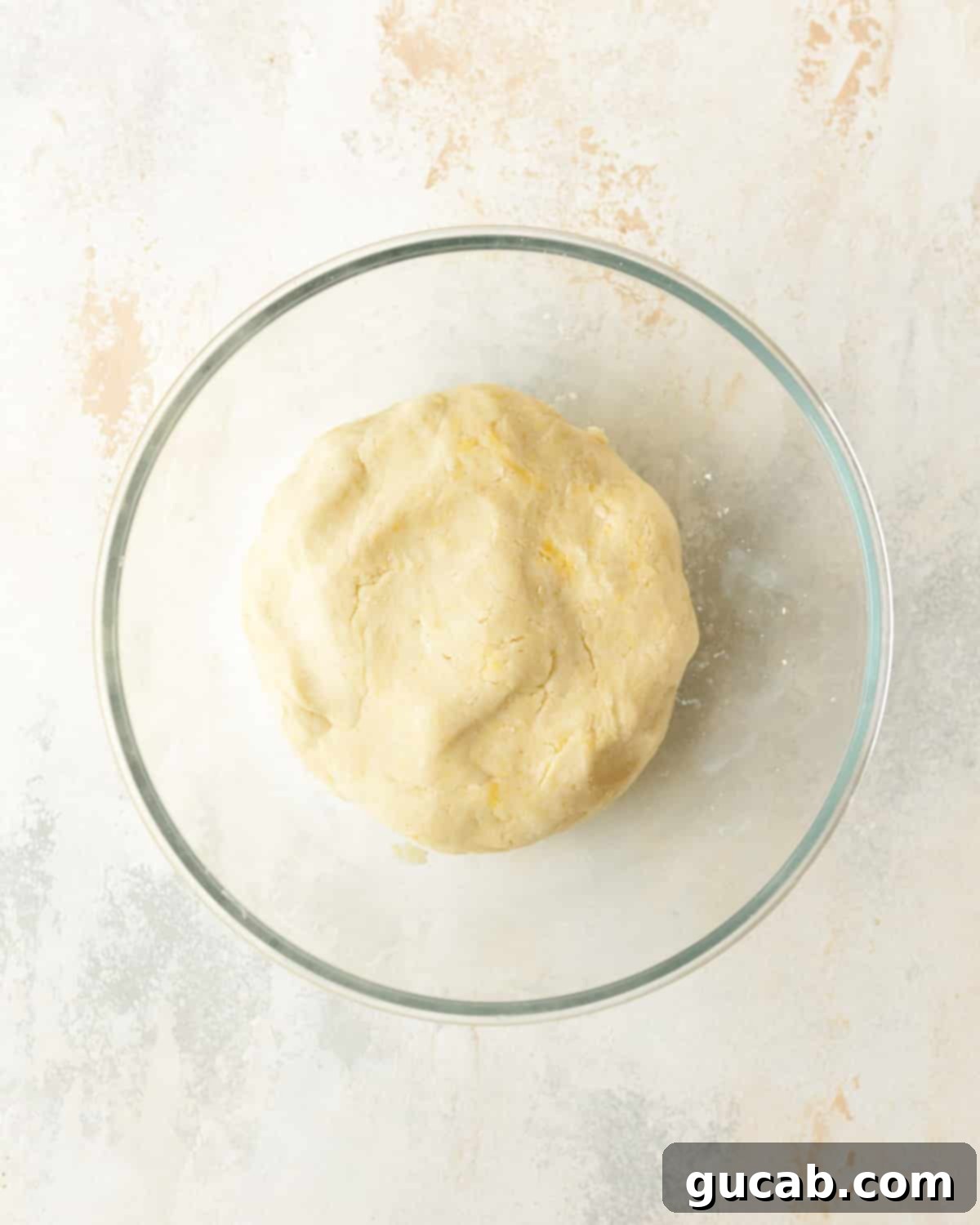 Gluten-free pie dough formed into a disc in a bowl, ready for chilling.