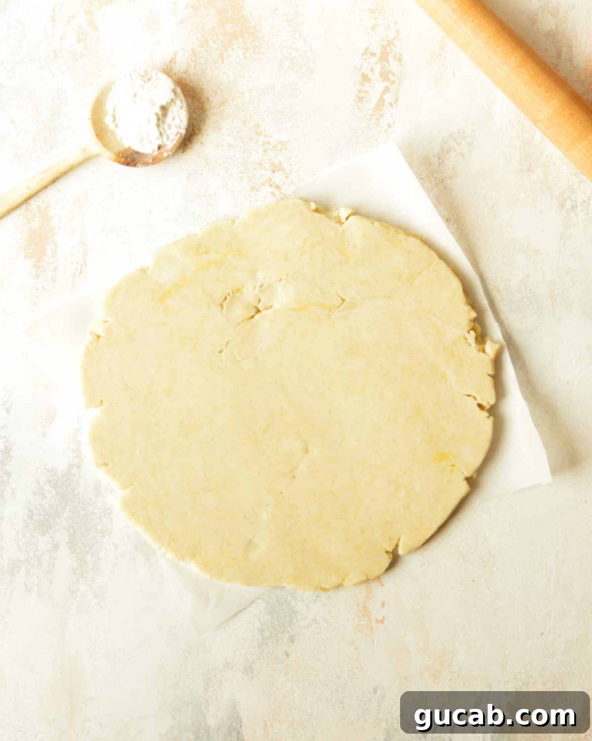 Gluten-free pie dough rolled out into a large circle on a floured surface.
