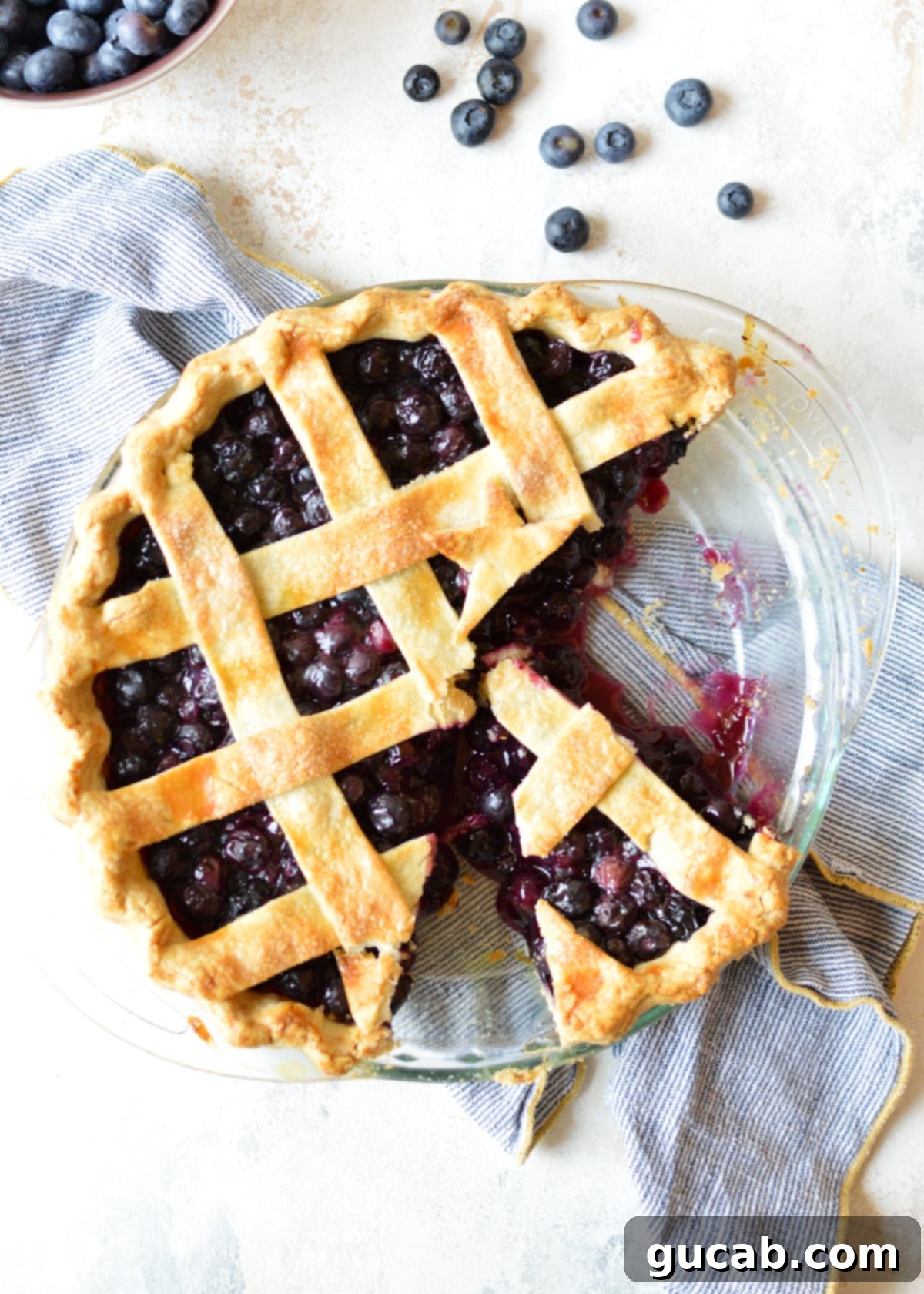 A freshly baked gluten-free blueberry pie with a slice removed, revealing the perfectly jammy blueberry filling.