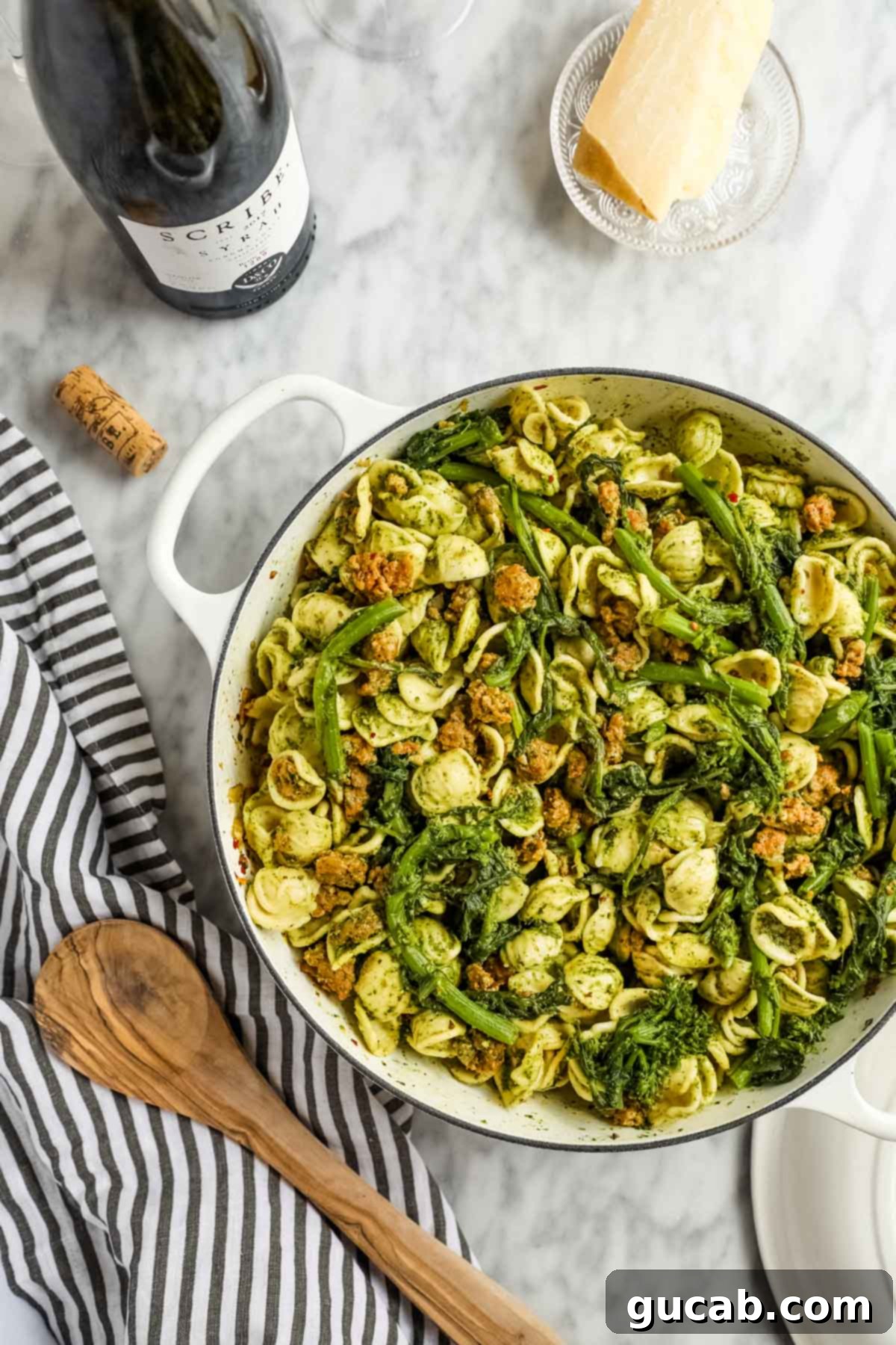 a dutch oven filled with vibrant pesto pasta, sausage, and rapini