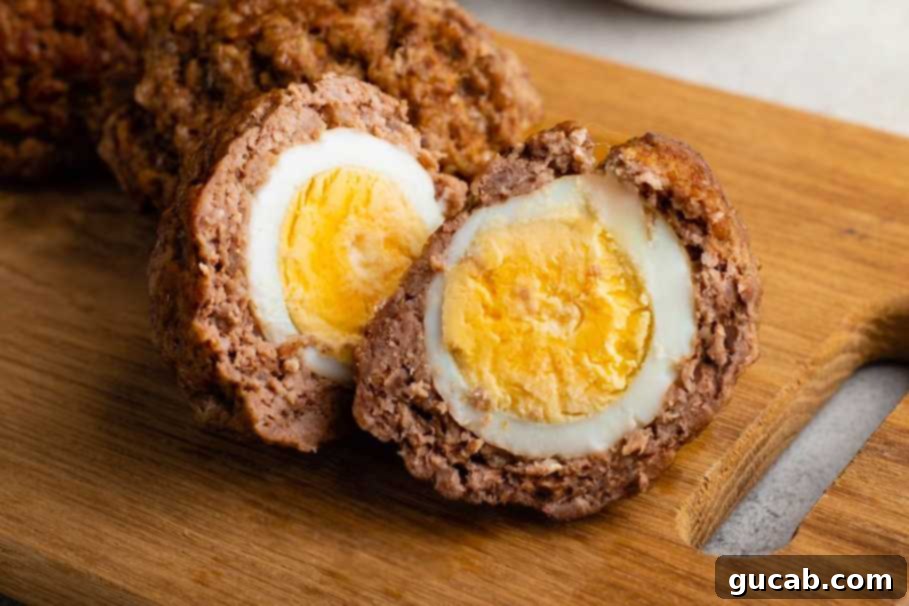 two Instant Pot scotch eggs sliced on a wooden cutting board