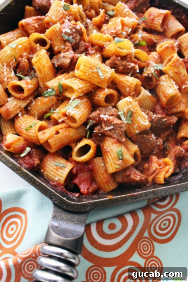 rigatoni and sausage cooking in a savory sauce in a skillet