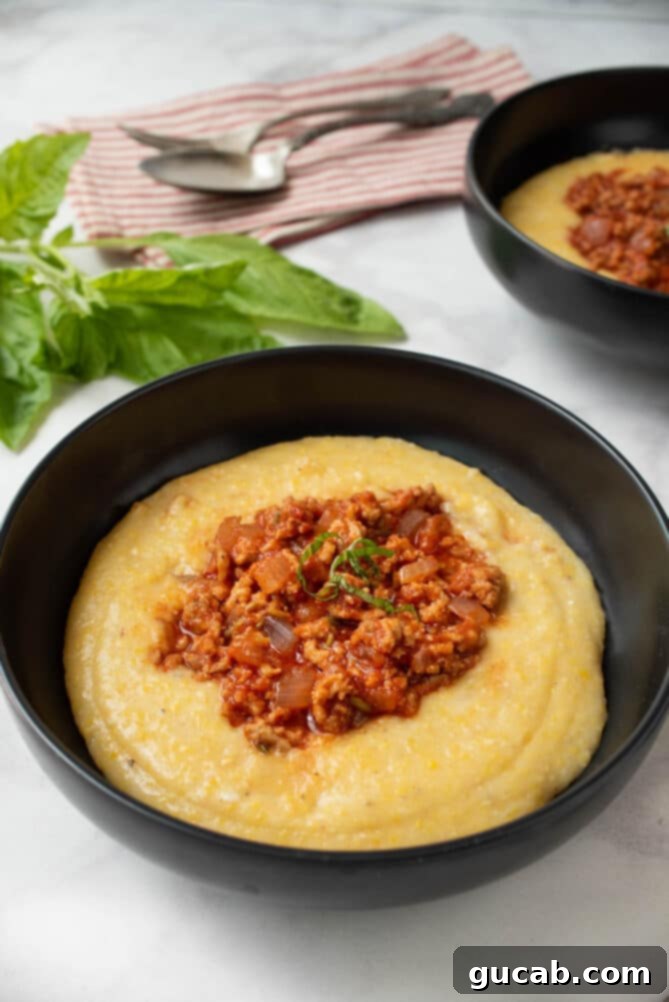 a comforting bowl of polenta topped with sausage and tomato sauce