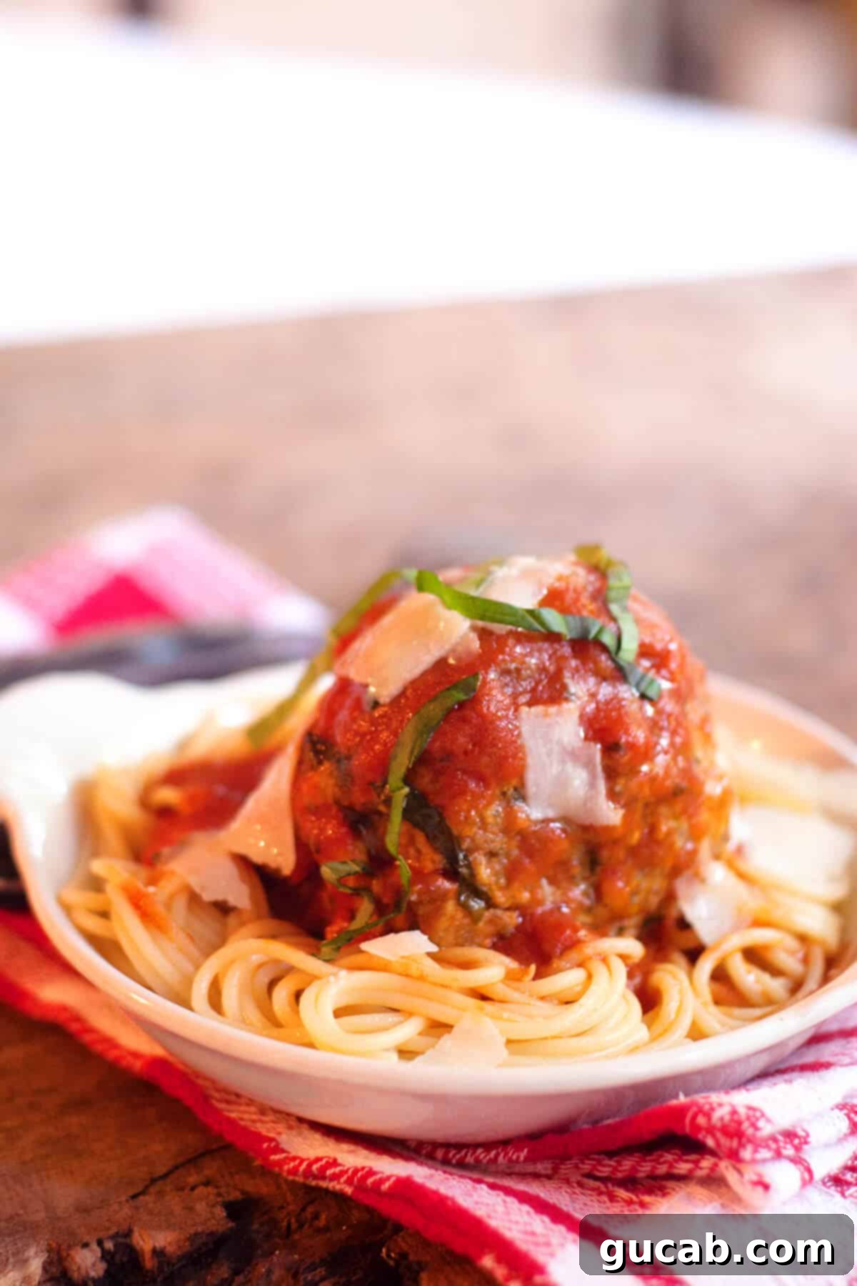 a generously sized jumbo meatball resting on a bed of spaghetti