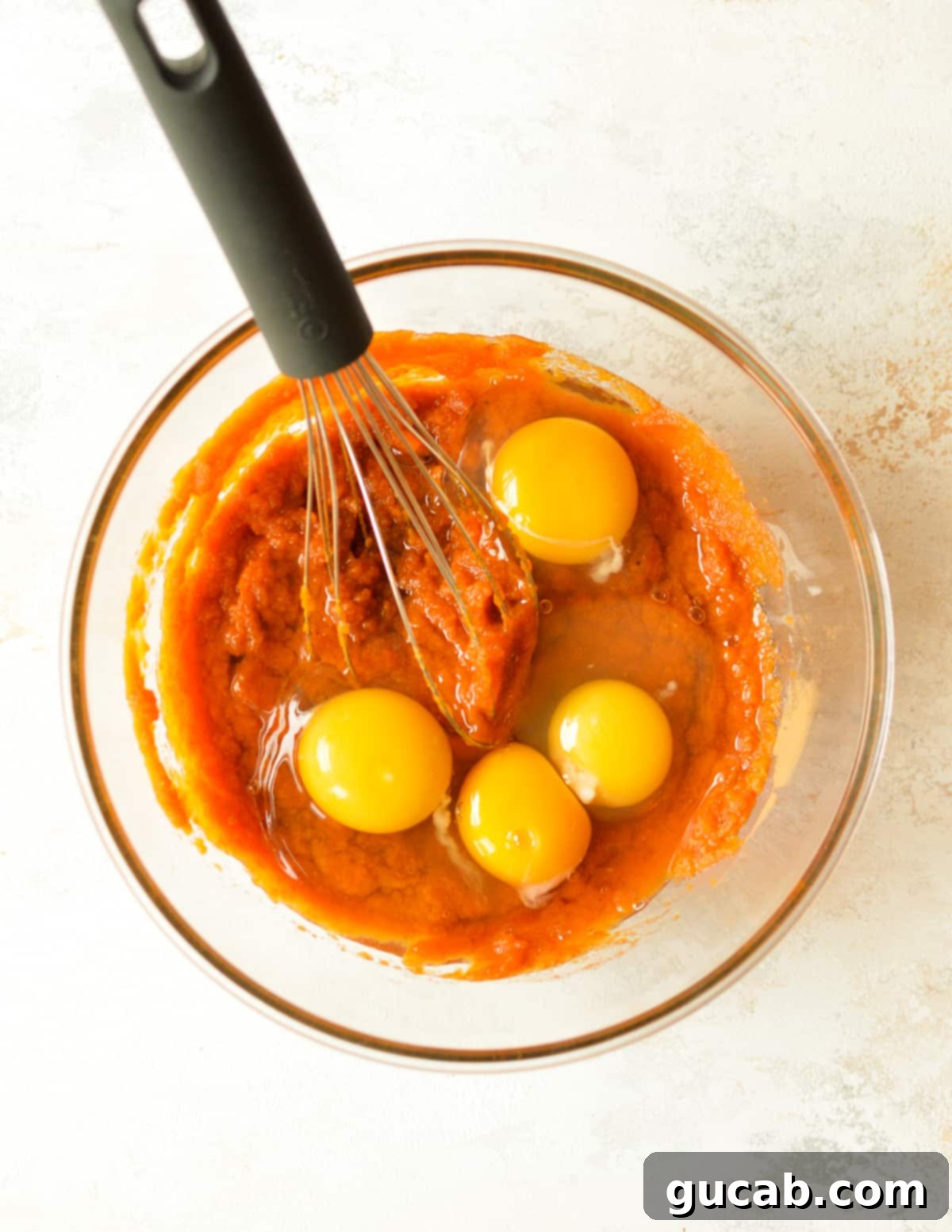 Pumpkin puree mixture in a bowl with eggs on top, ready to be whisked together.