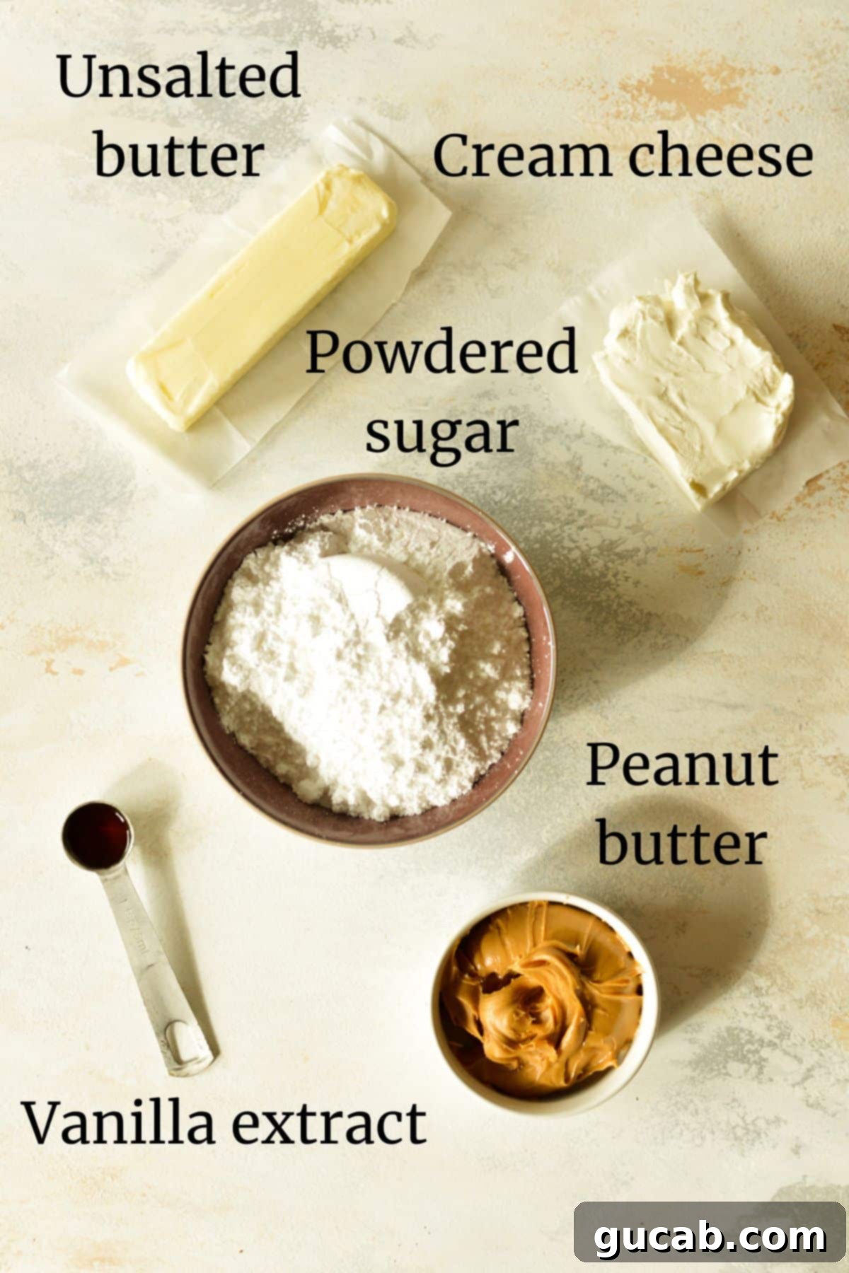 A flat lay showing softened butter, full-fat cream cheese, finely powdered sugar, clear vanilla extract, and creamy peanut butter – all essential for the frosting recipe.