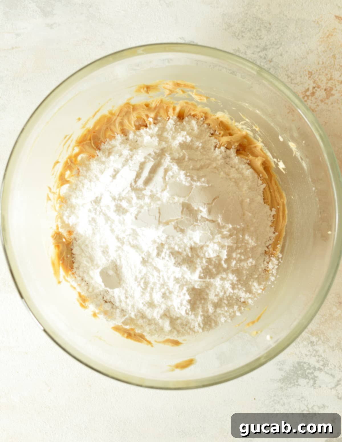Creamed butter, cream cheese, and peanut butter mixture with a mound of powdered sugar on top, ready for final mixing.