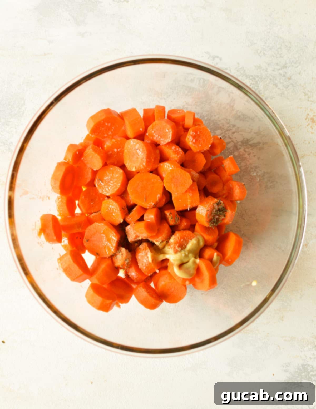a bowl of sliced carrots with dijon mustard, olive oil, and spices