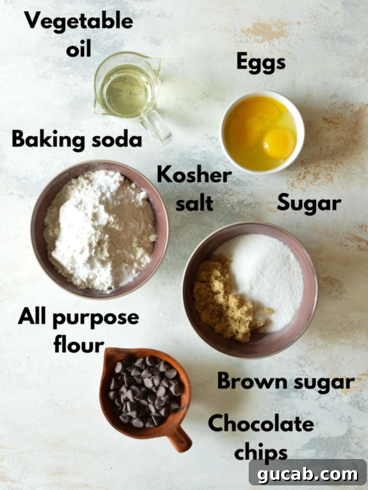 A flat lay of cookie ingredients: eggs, all-purpose flour, sugar, chocolate chips, and a bottle of vegetable oil.