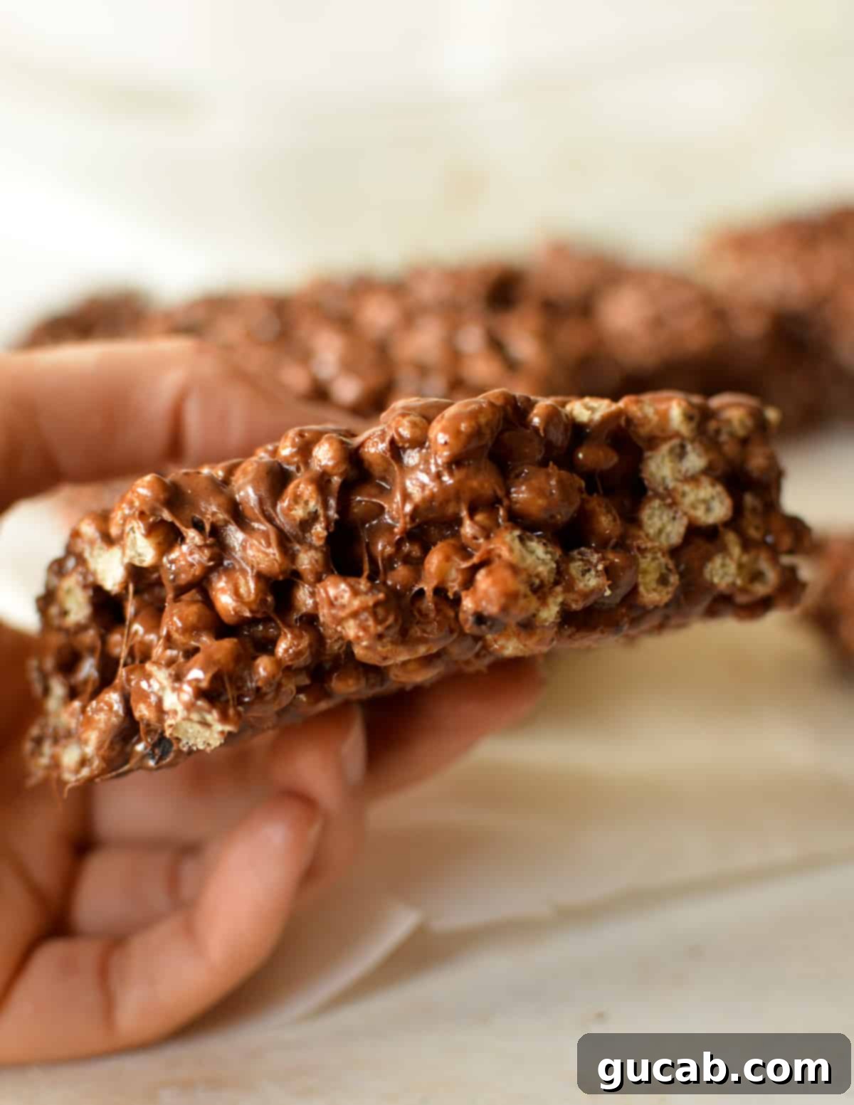 A hand gently holding a perfectly cut homemade chocolate protein rice crispy treat, ready to be enjoyed.