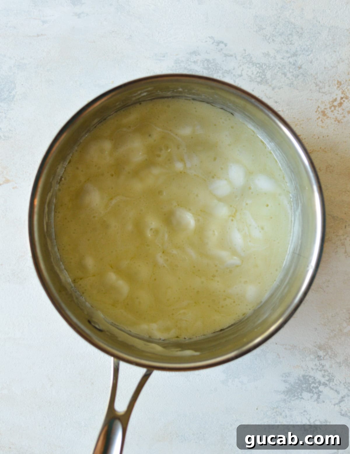 Melted butter and mini marshmallows blending together in a pot to form a smooth, gooey mixture.