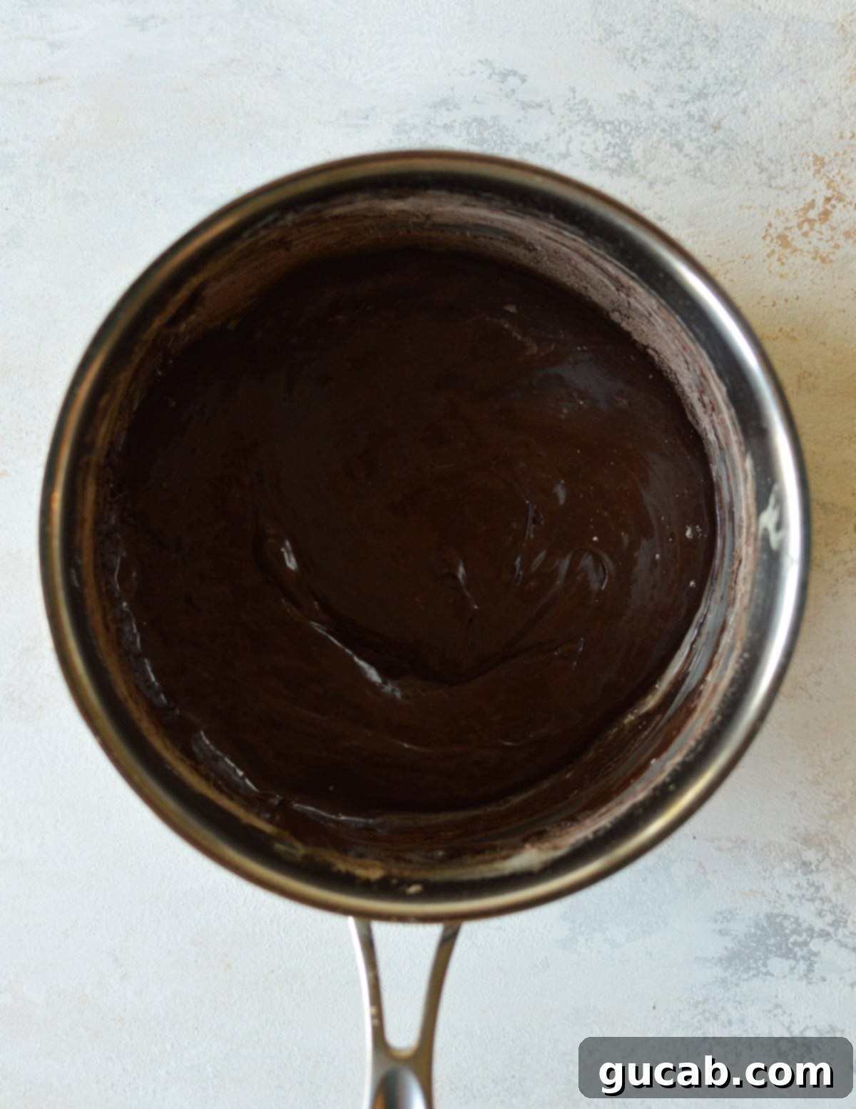 Melted marshmallows and butter, now infused with chocolate protein powder and cocoa powder, creating a rich, dark mixture.