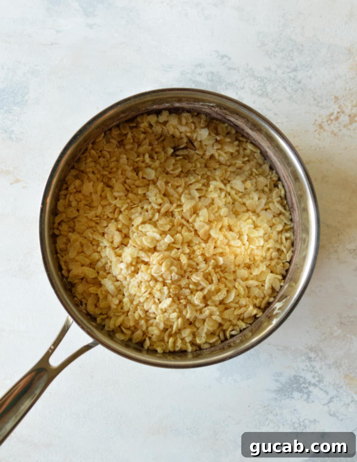 Rice crispy cereal being mixed into the rich chocolate marshmallow blend in a large pot, ensuring even coating.