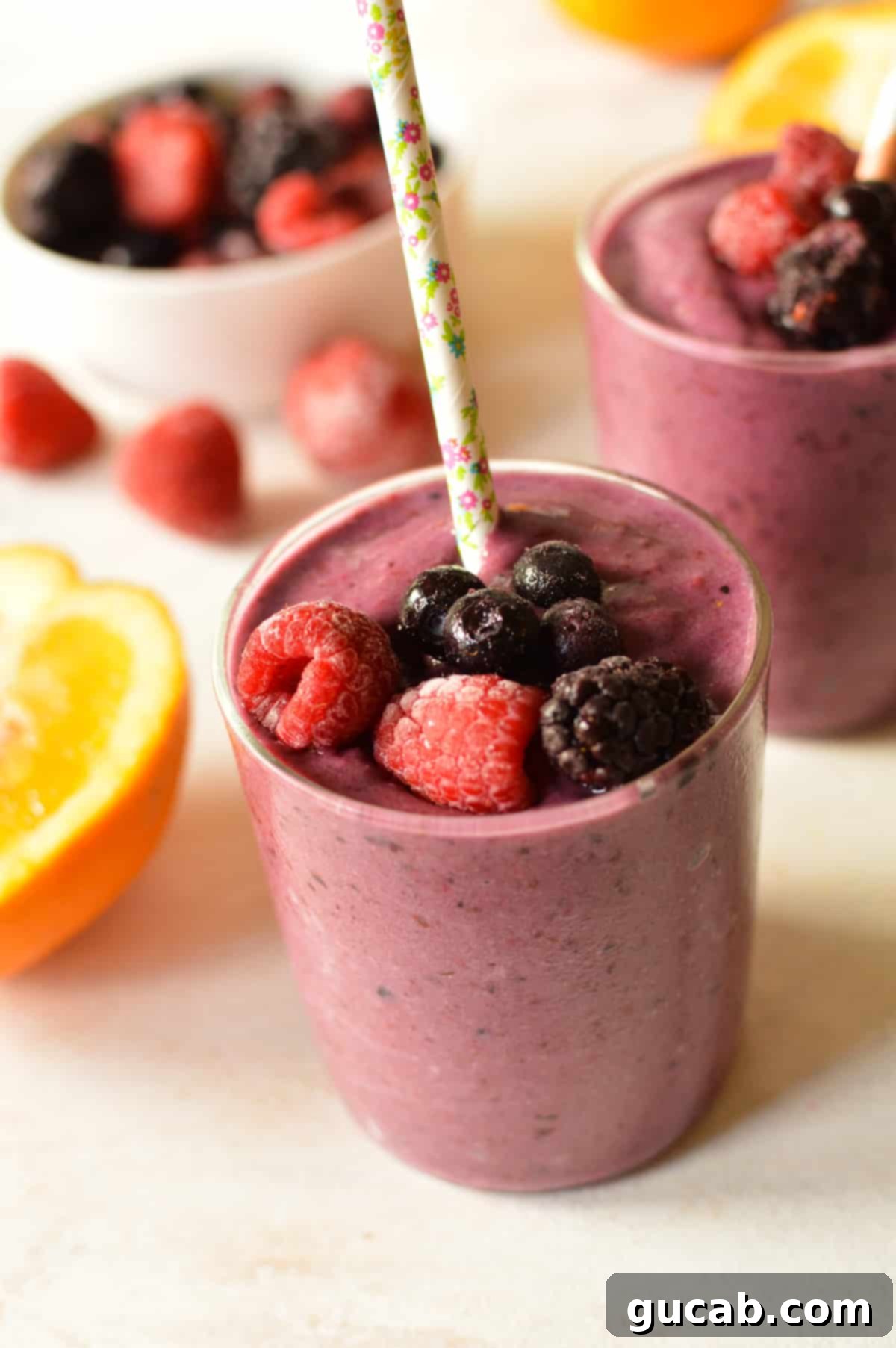 a glass of berry smoothie with berries on top