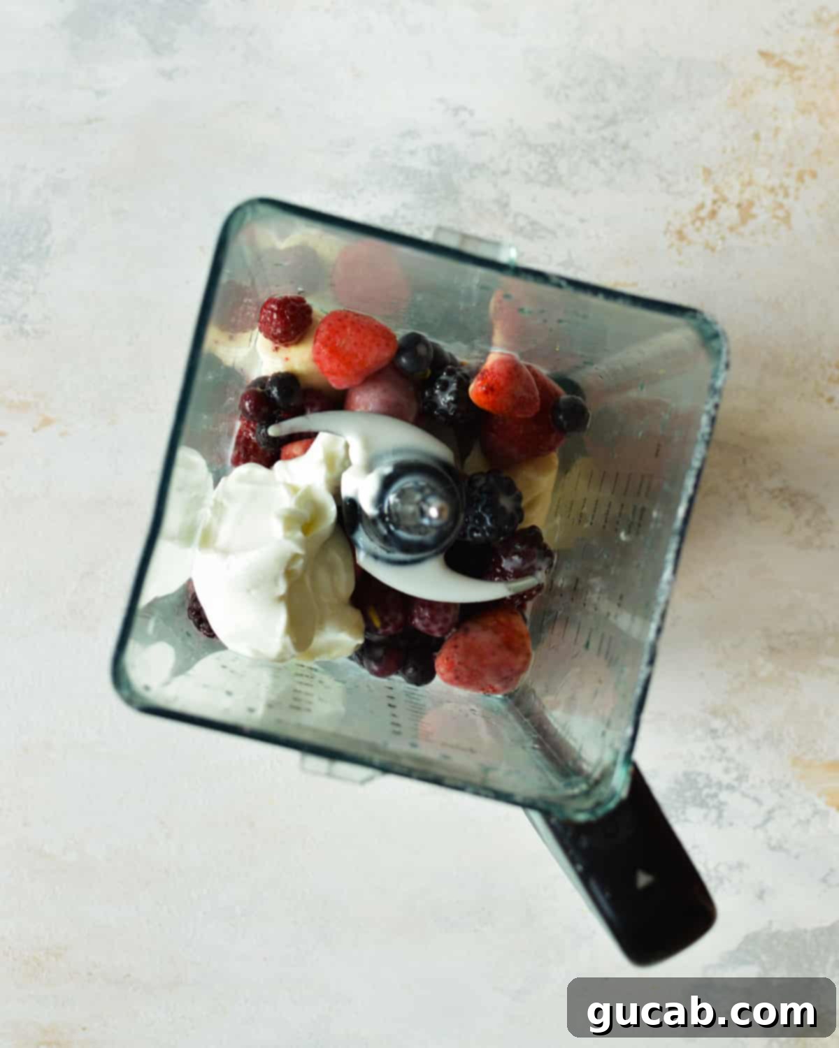 a blender with berries, yogurt, banana, and almond milk
