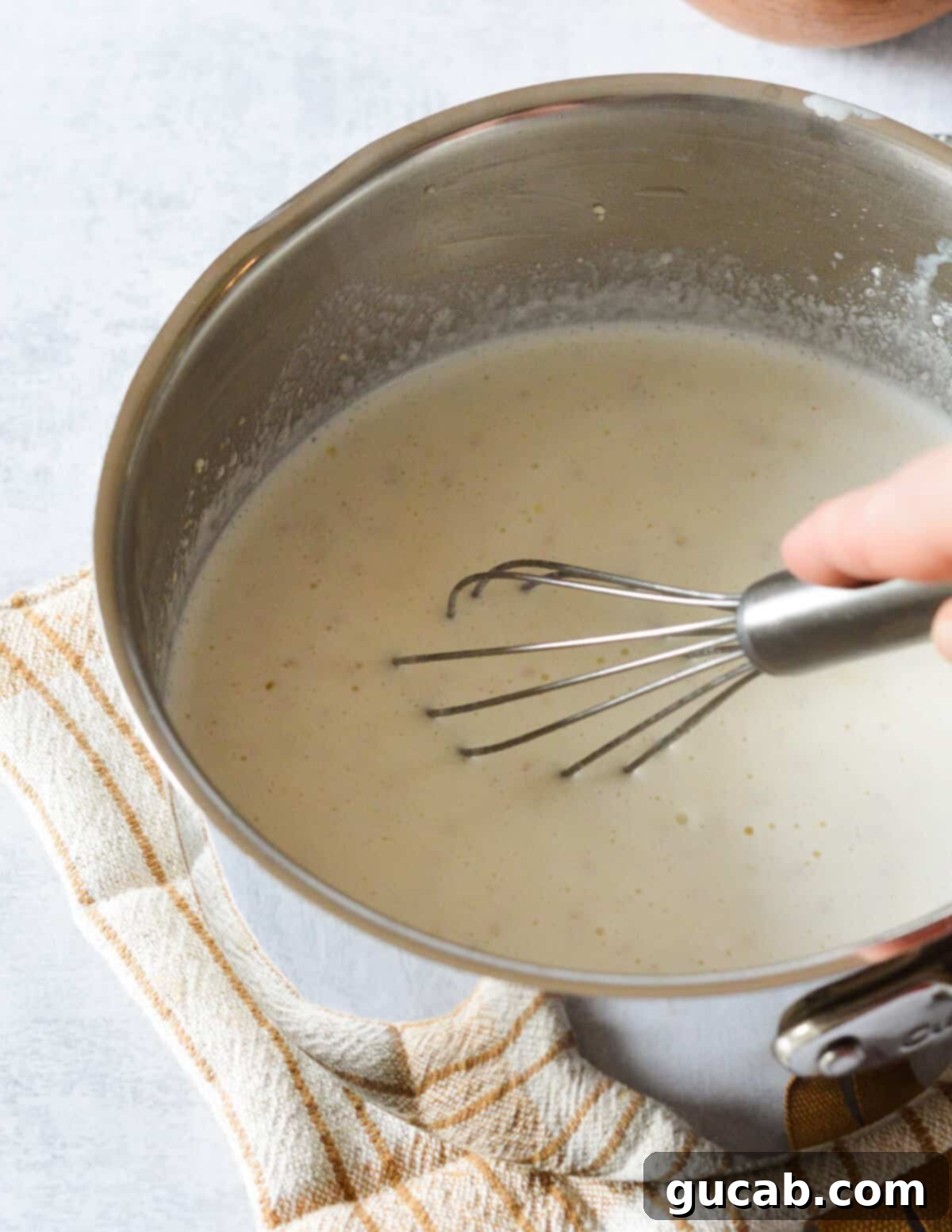 Hearty Creamy Grits 6 A whisk stirring the grits and milk mixture in a saucepan, ensuring no lumps form.