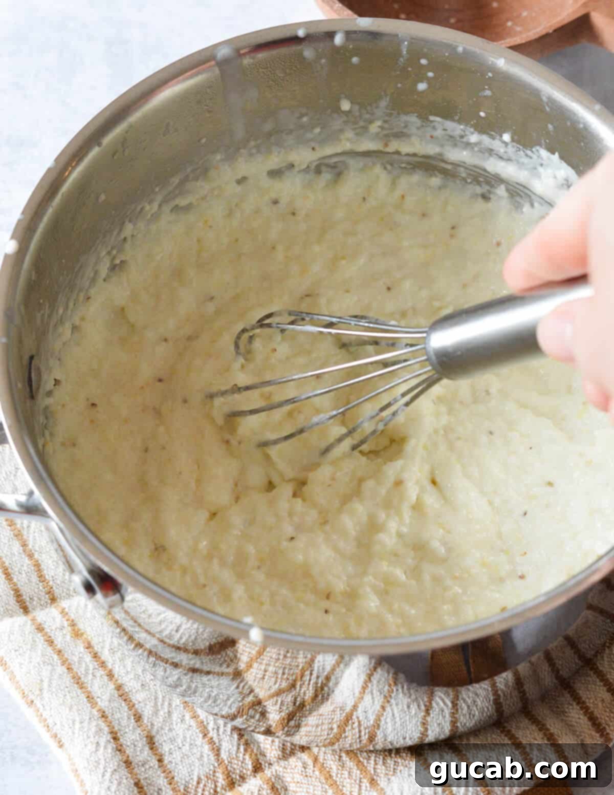 Rich and Creamy Grits 7 Continuously stirring grits in a pot as they thicken, crucial for creamy results.