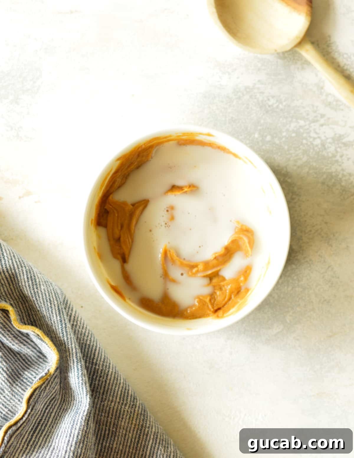 A bowl showcasing the combined peanut butter, maple syrup, and almond milk, stirred to a smooth consistency.