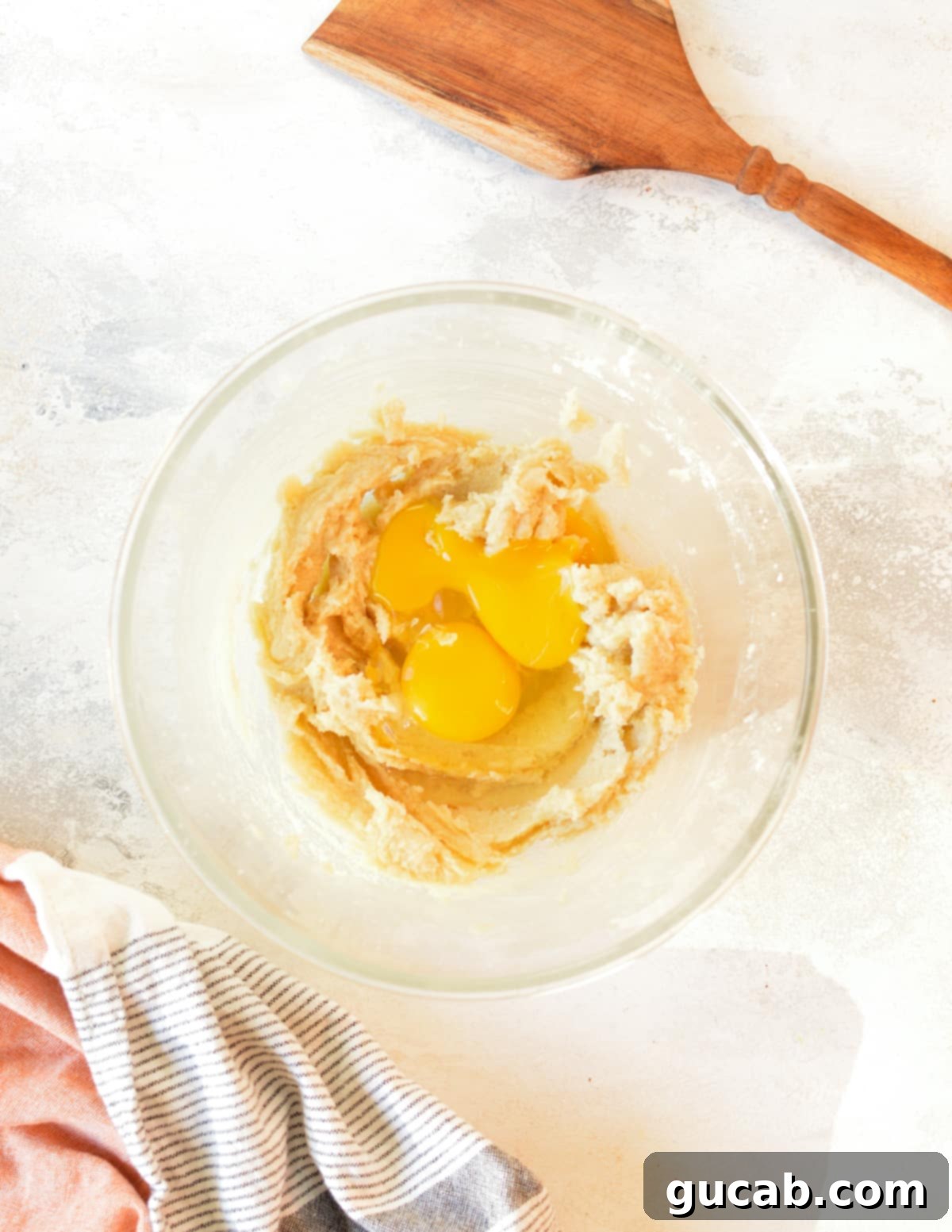 creamed butter and sugar mixture with a whole egg and an egg yolk on top, ready to be mixed