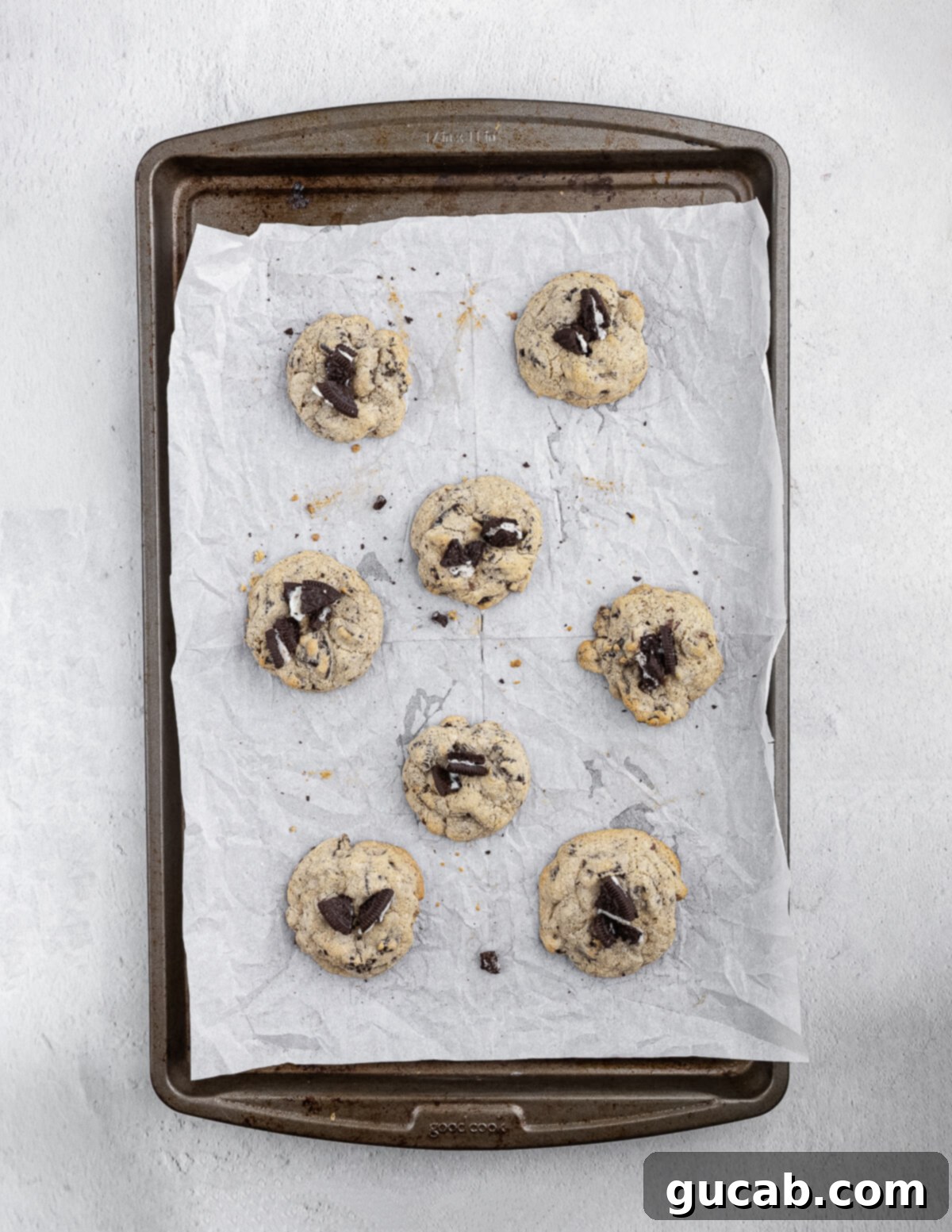 Freshly baked cookies and cream cookies cooling on a sheet pan, showing their perfect golden edges and inviting textures.