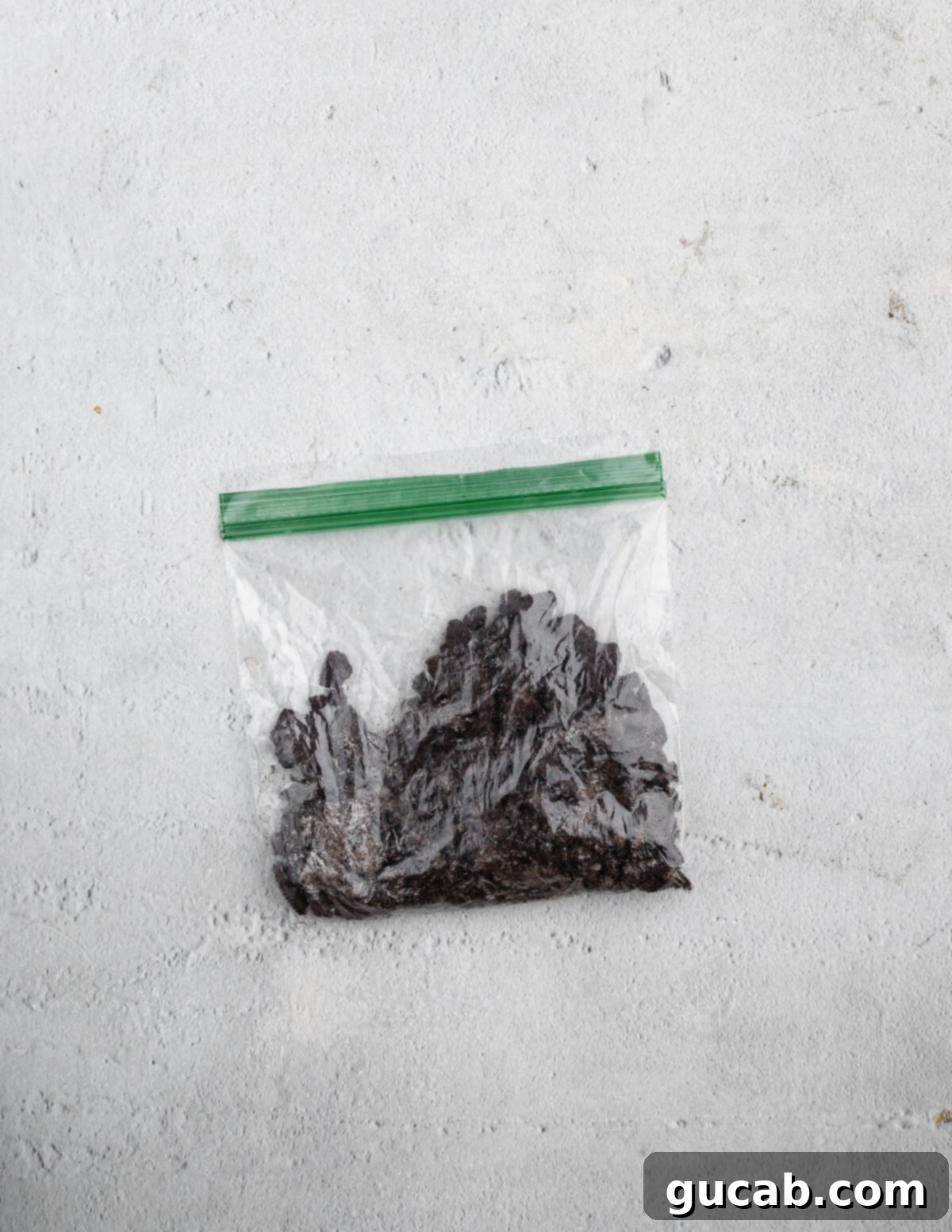 A clear zip-top bag filled with crushed Oreo cookie crumbs, showcasing the varying textures from fine powder to small chunks.