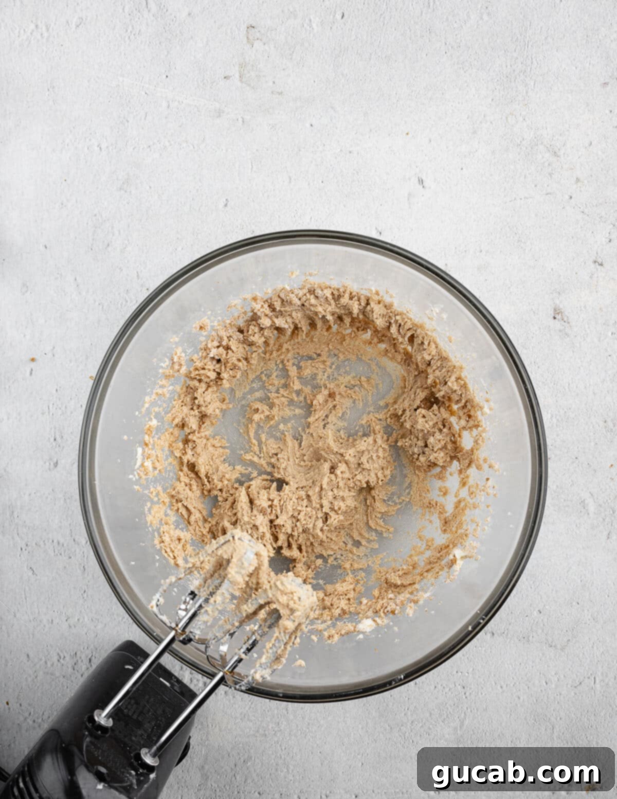 A close-up of butter, granulated sugar, and brown sugar creamed together in a mixing bowl, showing a light and fluffy texture.