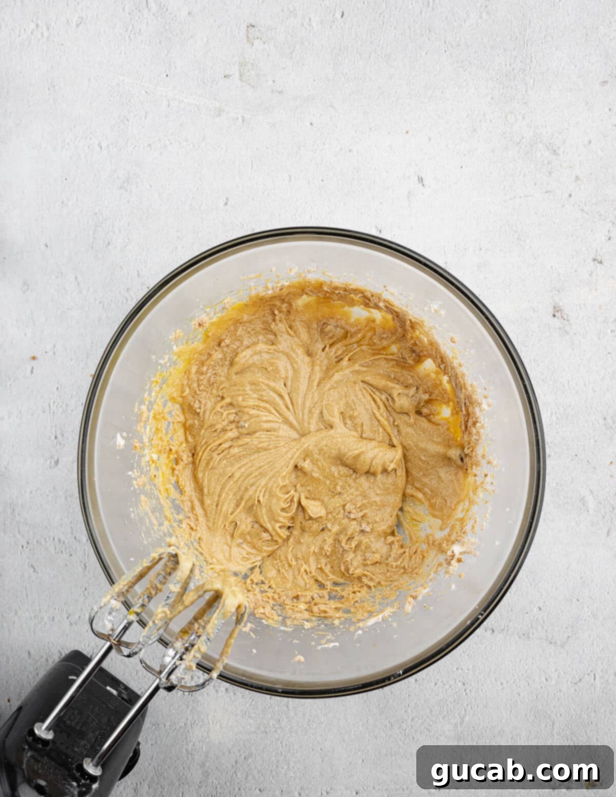 The thoroughly combined mixture of creamed butter, sugars, and eggs in a mixing bowl, appearing smooth and uniform.