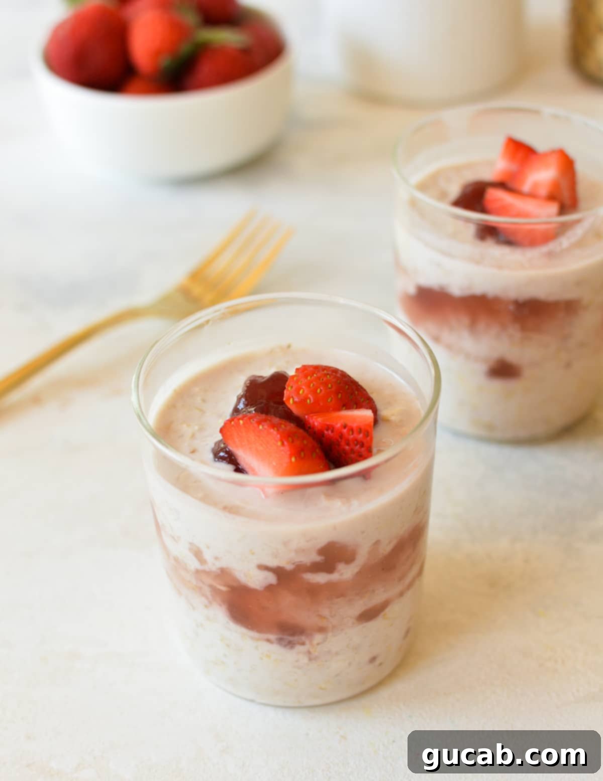 Two glass jars filled with prepared overnight oats, topped with vibrant jam and fresh berries, ready for refrigeration.
