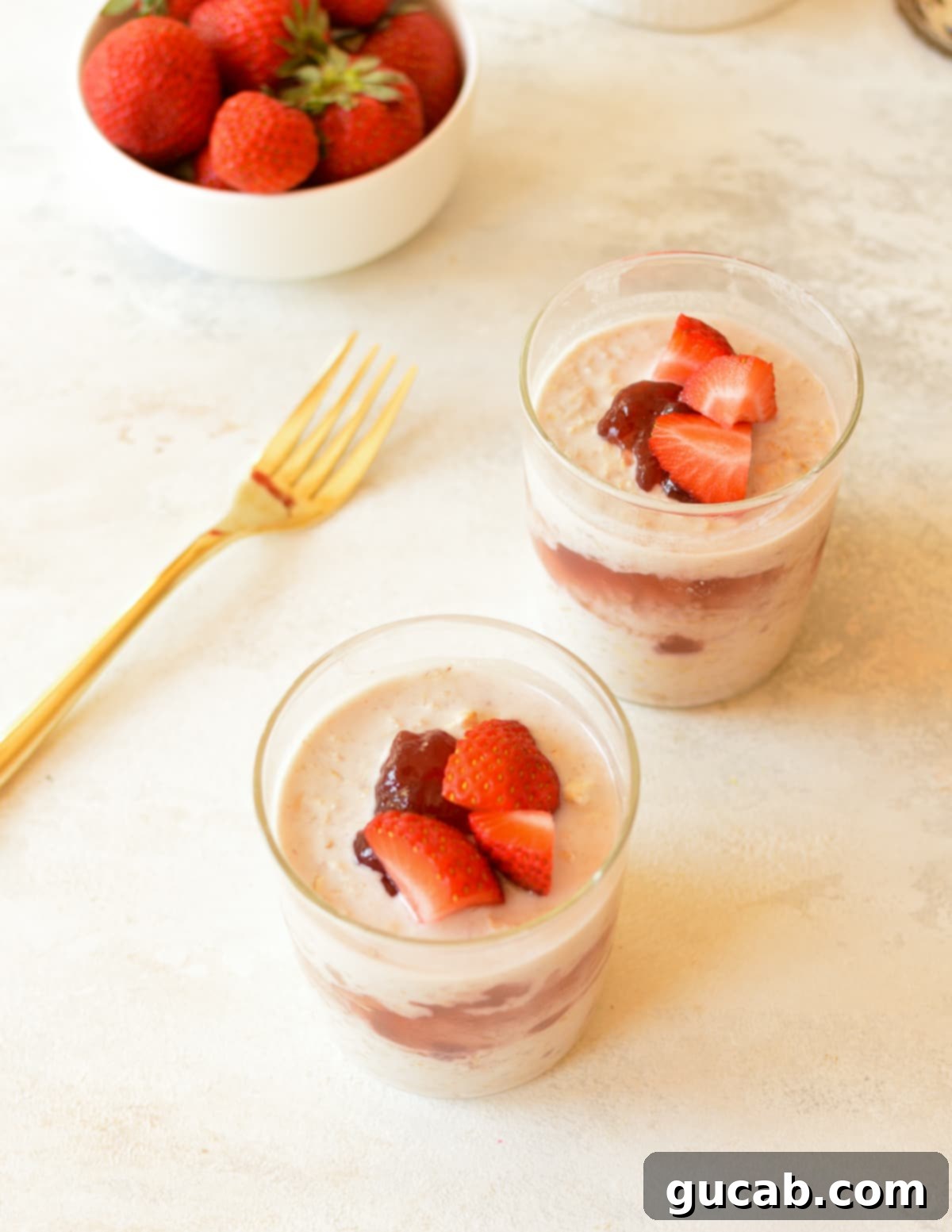 Two aesthetically pleasing cups of jammy overnight oats, topped with fresh berries and a drizzle of extra jam, ready for serving.