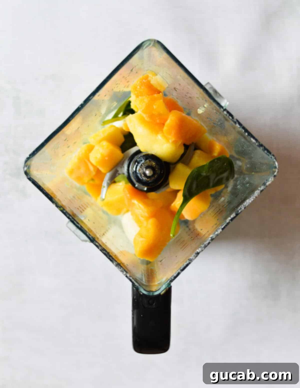 Island Iron Infusion 5 frozen mango, pineapple, and spinach in a blender.