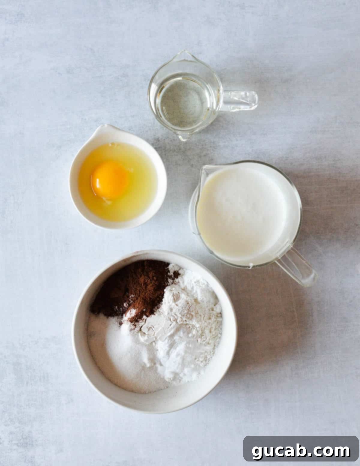 Guilt-Free Chocolate Pancake Indulgence 3 An array of ingredients including vegetable oil, egg, buttermilk, gluten-free flour, cocoa powder, and baking powder, laid out for chocolate pancake preparation.