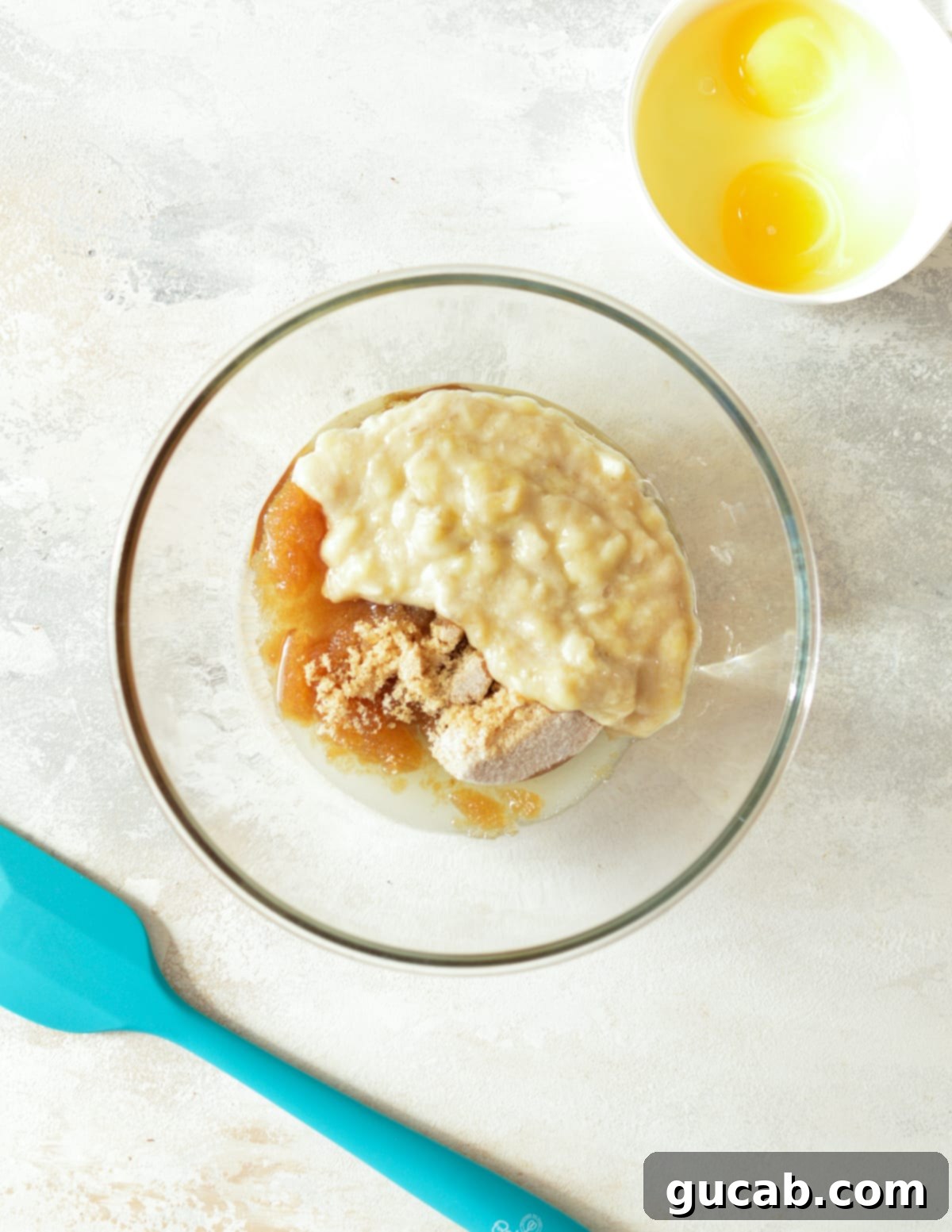 mashed banana, sugar, and oil in a bowl. 