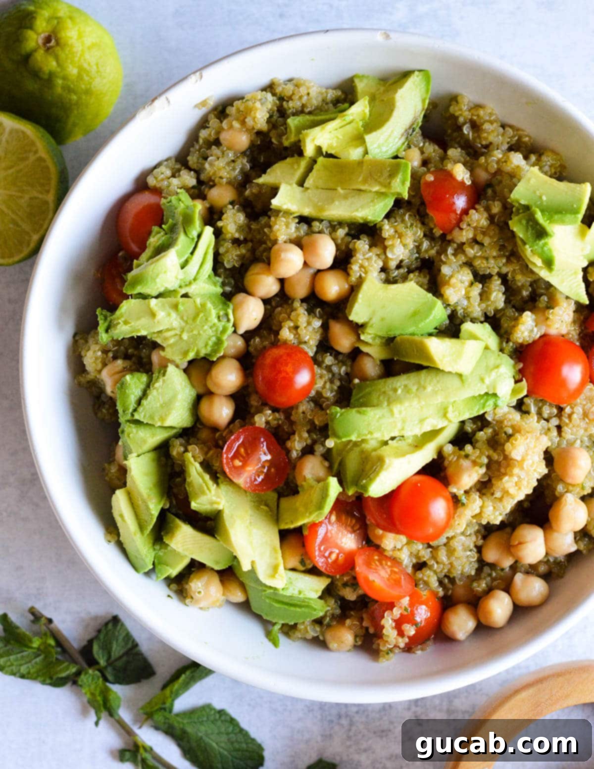 Vibrant Herb & Quinoa Power Bowl 2 a bowl of quinoa salad with sliced avocado and tomatoes on top.