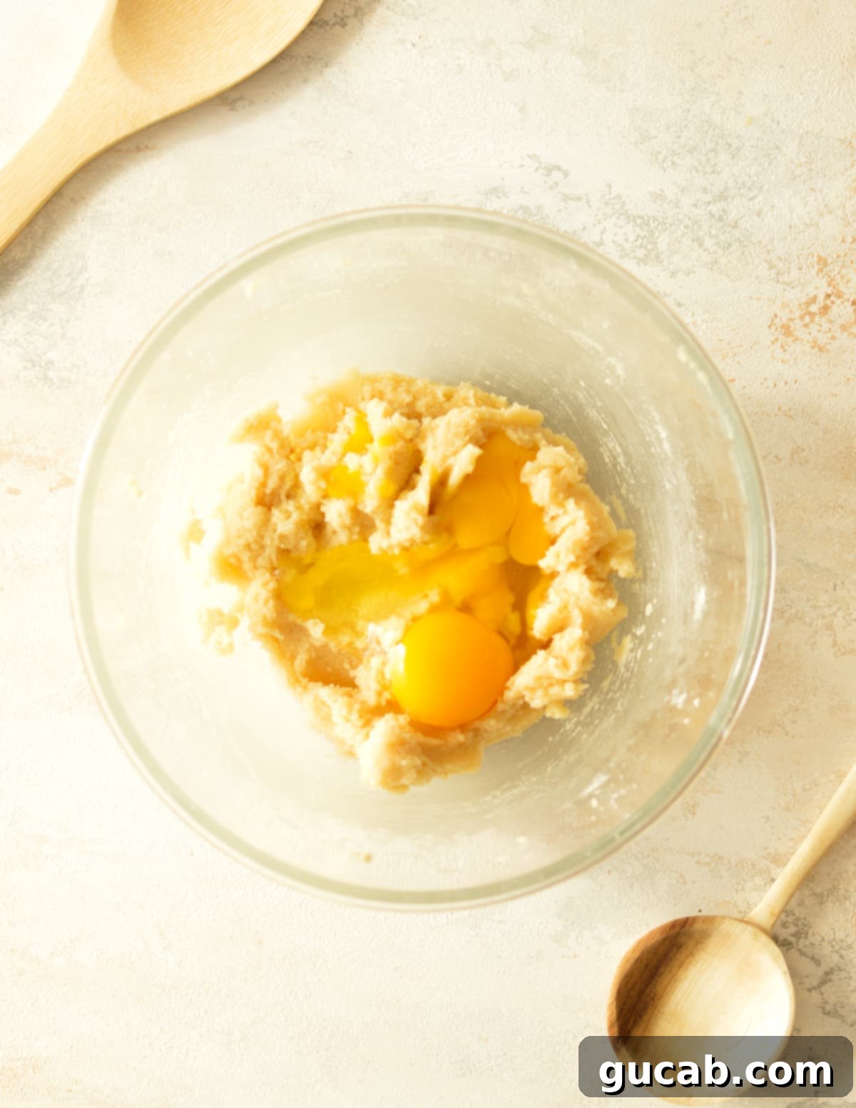 Chewy Nut Medley Cookies 5 Egg and an additional egg yolk carefully added on top of the smooth, creamed butter and sugar mixture in a bowl, ready for gentle mixing.