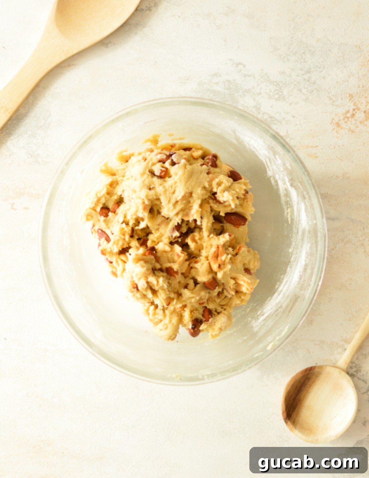 Chewy Nut Medley Cookies 7 Rich cookie dough with various chopped mixed nuts folded in, creating a textured batter ready for scooping and baking into delicious cookies.