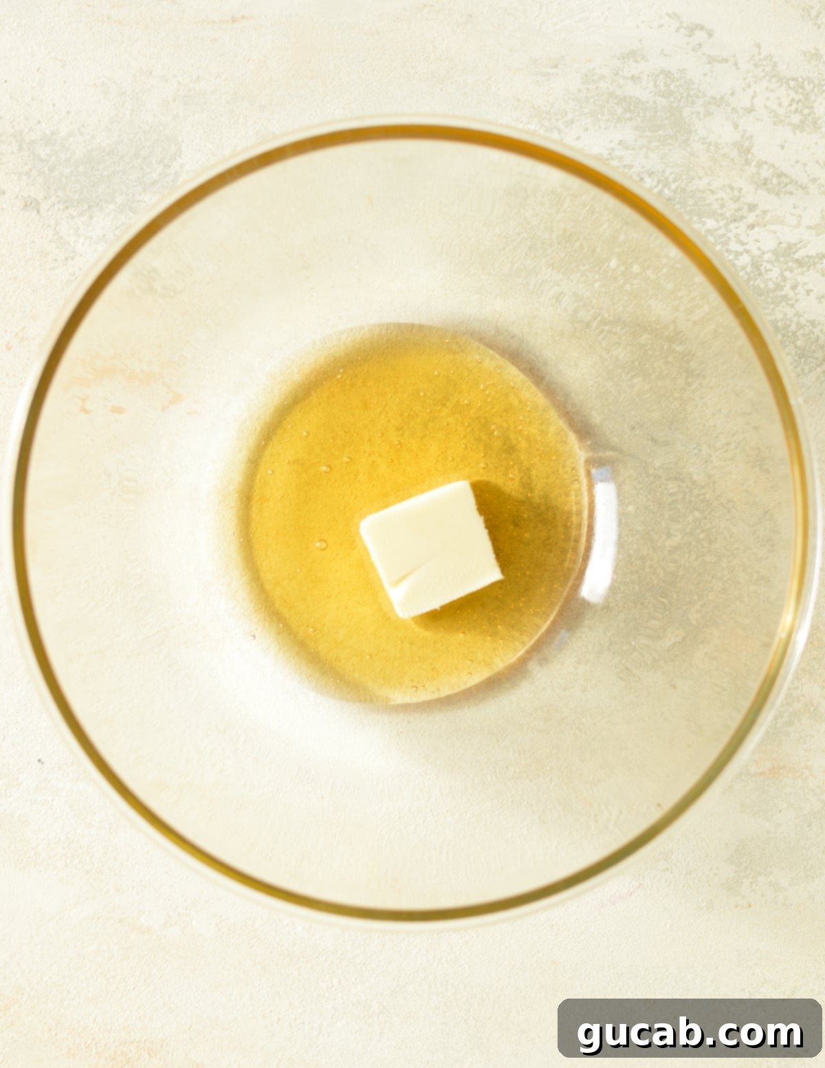 Close-up of honey and butter in a microwave-safe bowl before melting.