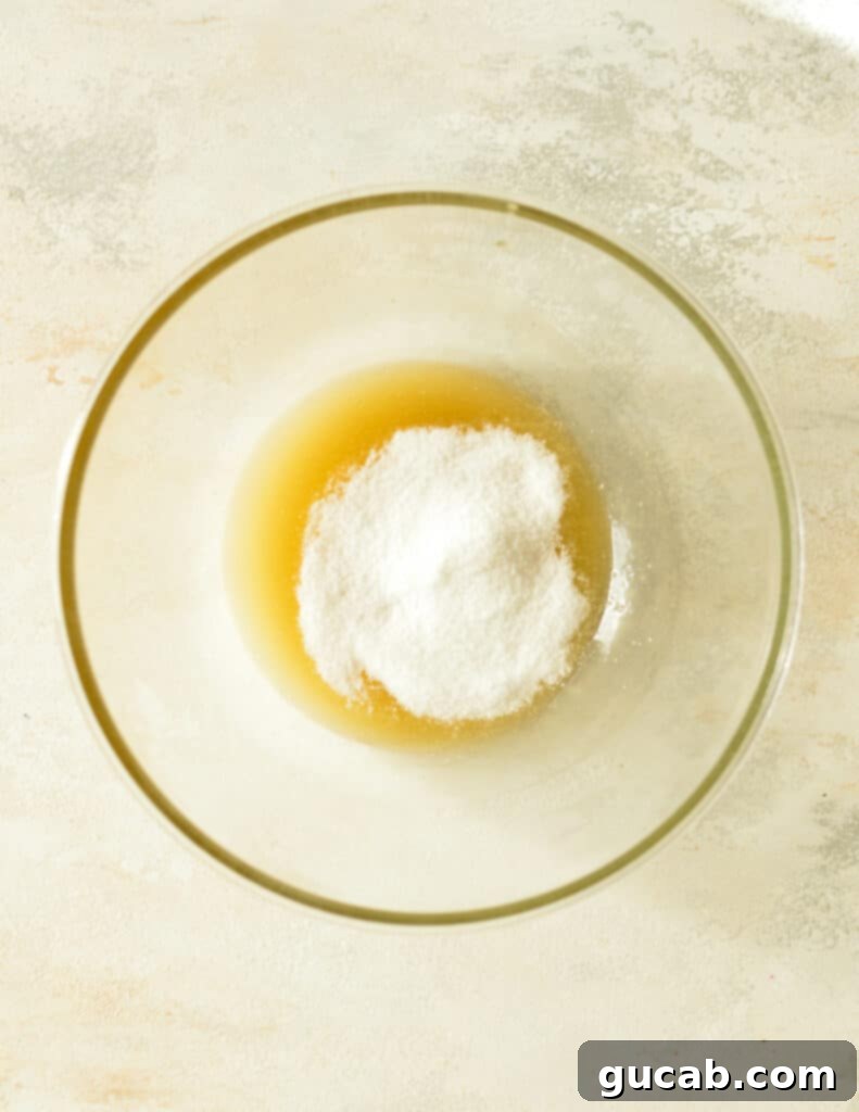 A bowl containing the honey, melted butter, sugar, and salt mixture, ready for cashews.