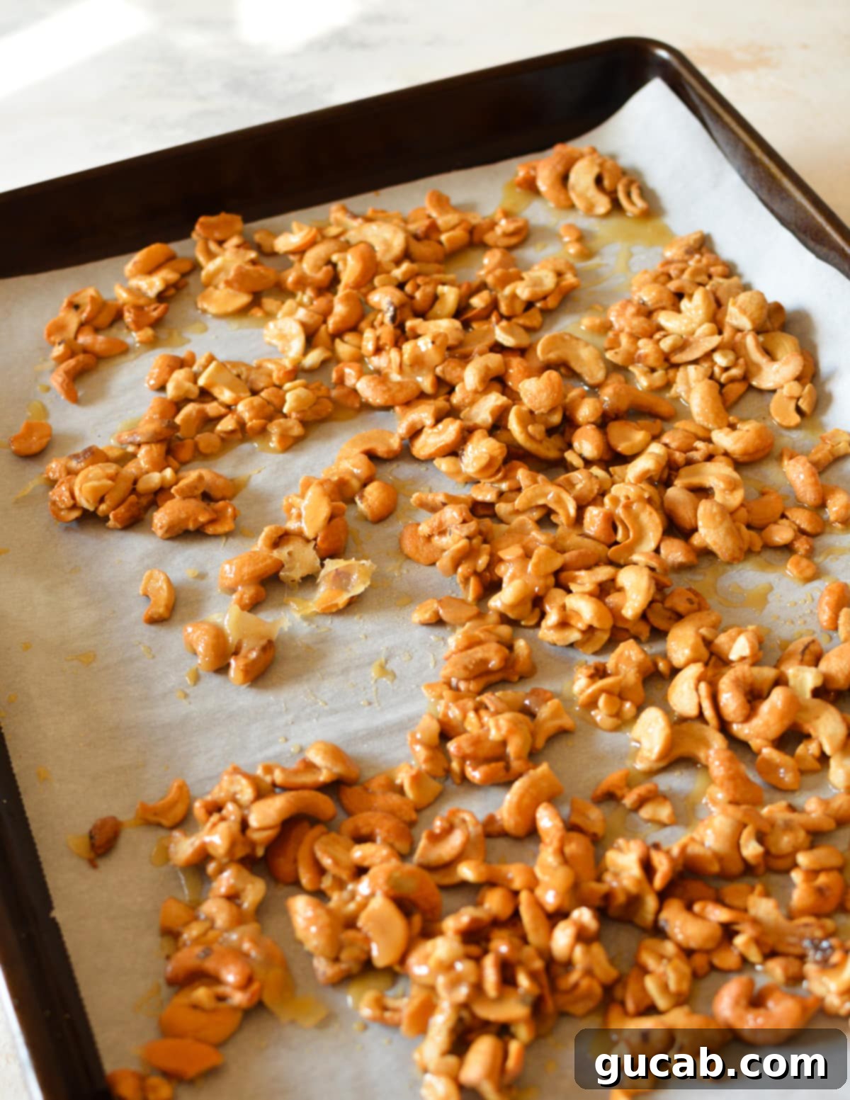 A sheet pan filled with freshly roasted, golden honey cashews, cooling down after being removed from the oven.