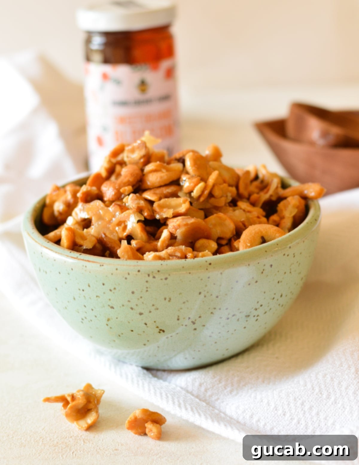 A close-up shot of a bowl filled with perfectly golden and glossy honey roasted cashews, ready to be served.