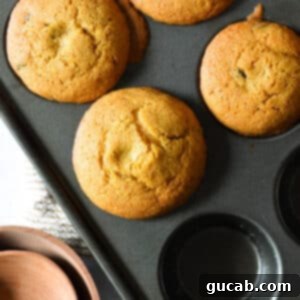 A close-up of a single gluten-free pumpkin muffin in a paper liner, showcasing its perfectly golden-brown top, ready to be enjoyed.
