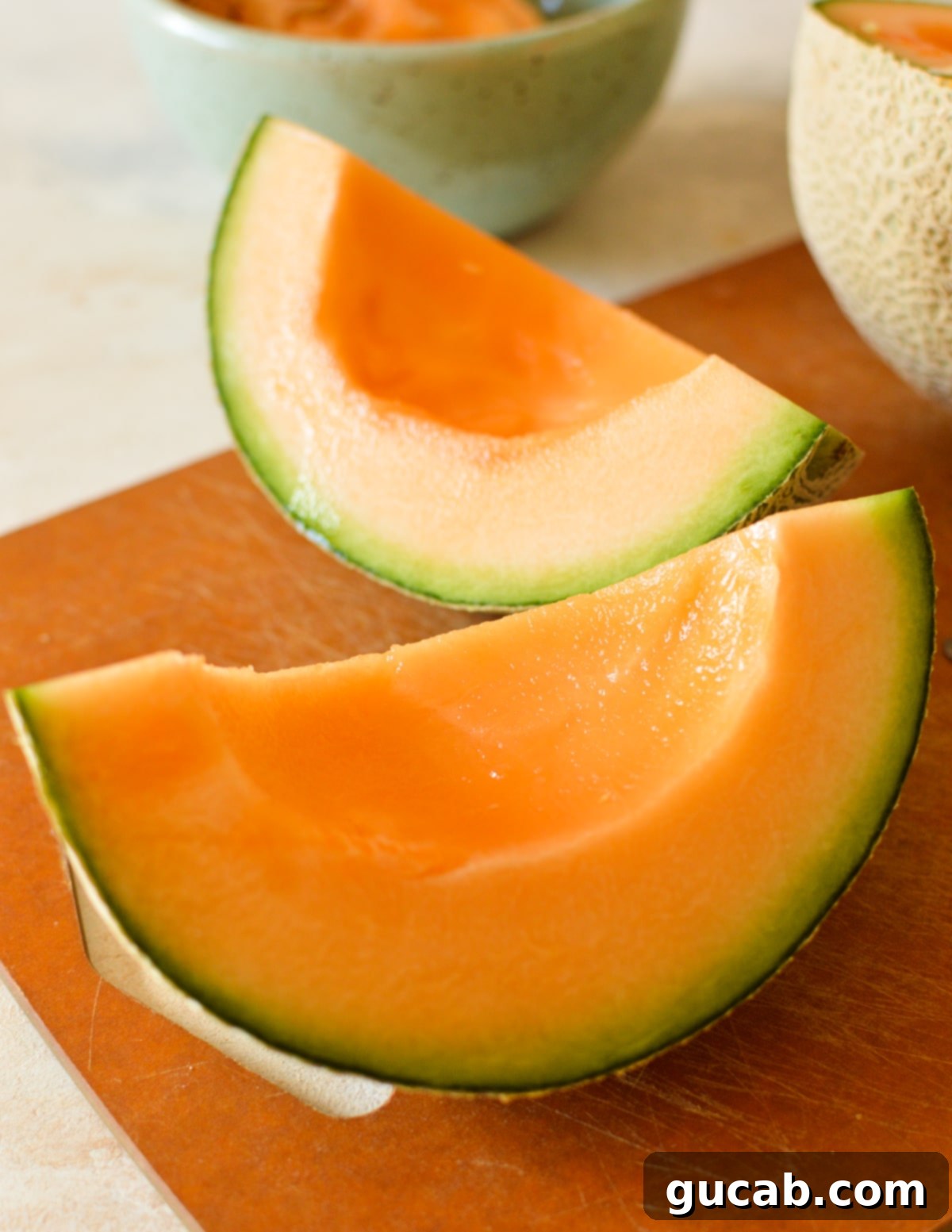 A third of a cantaloupe, cut into a wedge on a cutting board.