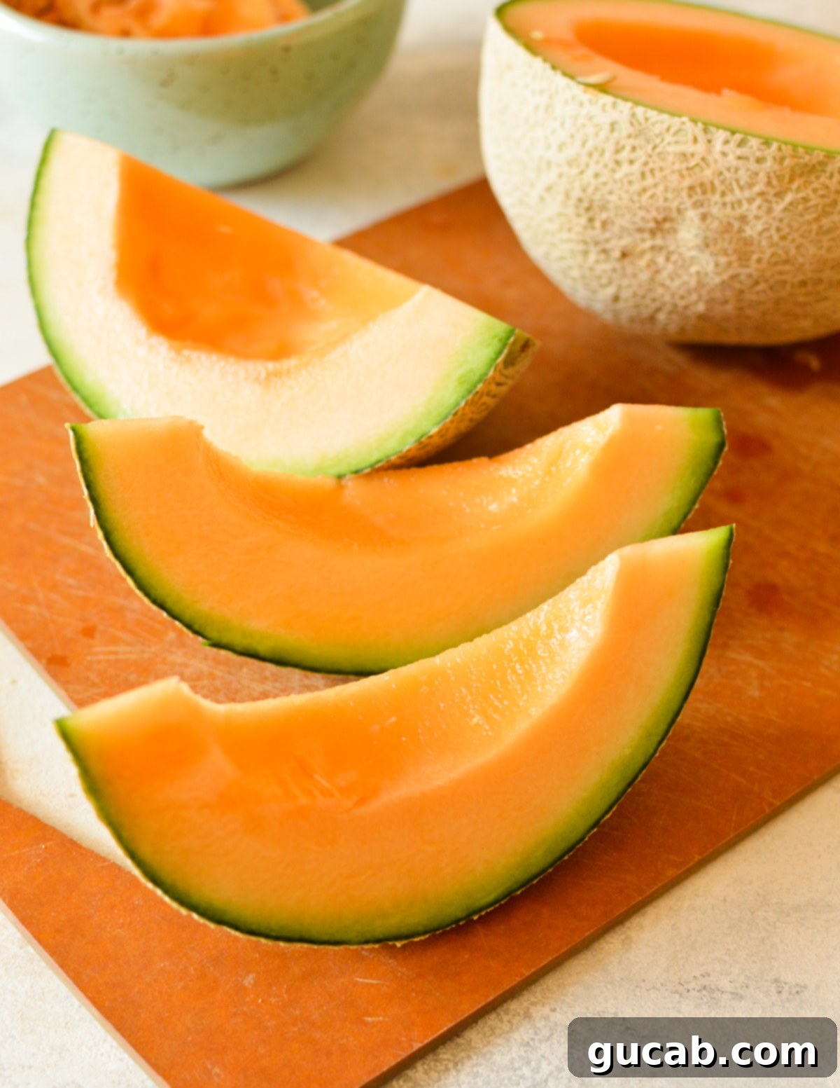 Several cantaloupe slices arranged on a cutting board.