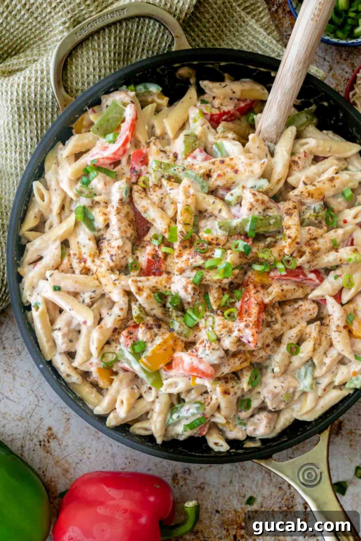 Budget-Friendly Feasts for a Crowd 6 A vibrant skillet filled with Jerk Chicken Rasta Pasta, featuring colorful bell peppers, pasta, and succulent chicken in a creamy sauce.