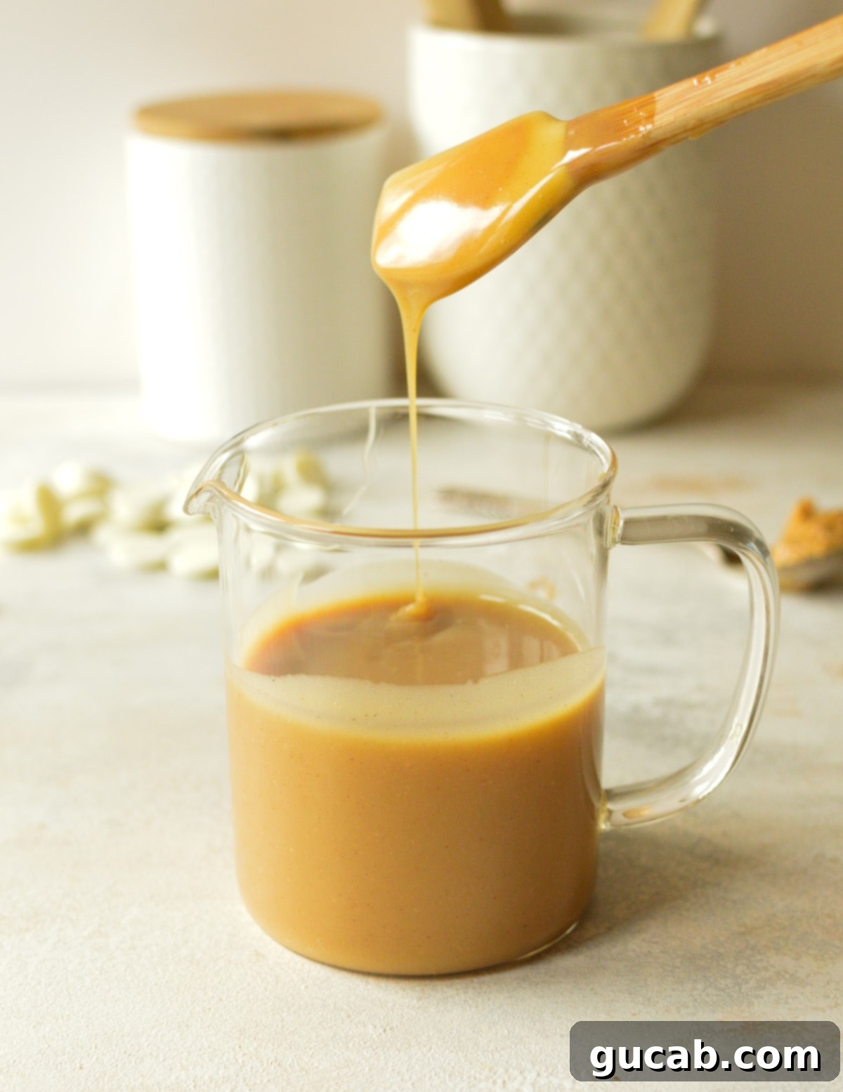 A spatula coated with creamy peanut butter ganache, ready to be spread or drizzled, highlighting its smooth and luxurious texture.