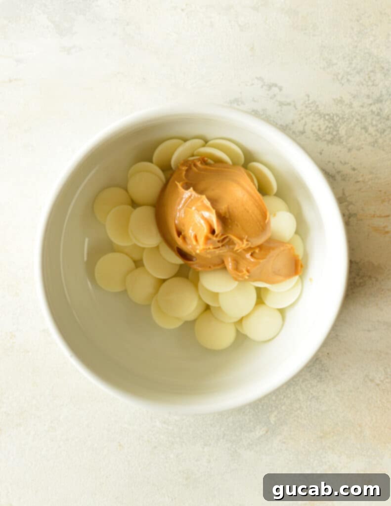 A bowl containing white chocolate melting wafers and creamy peanut butter, ready for the hot cream.
