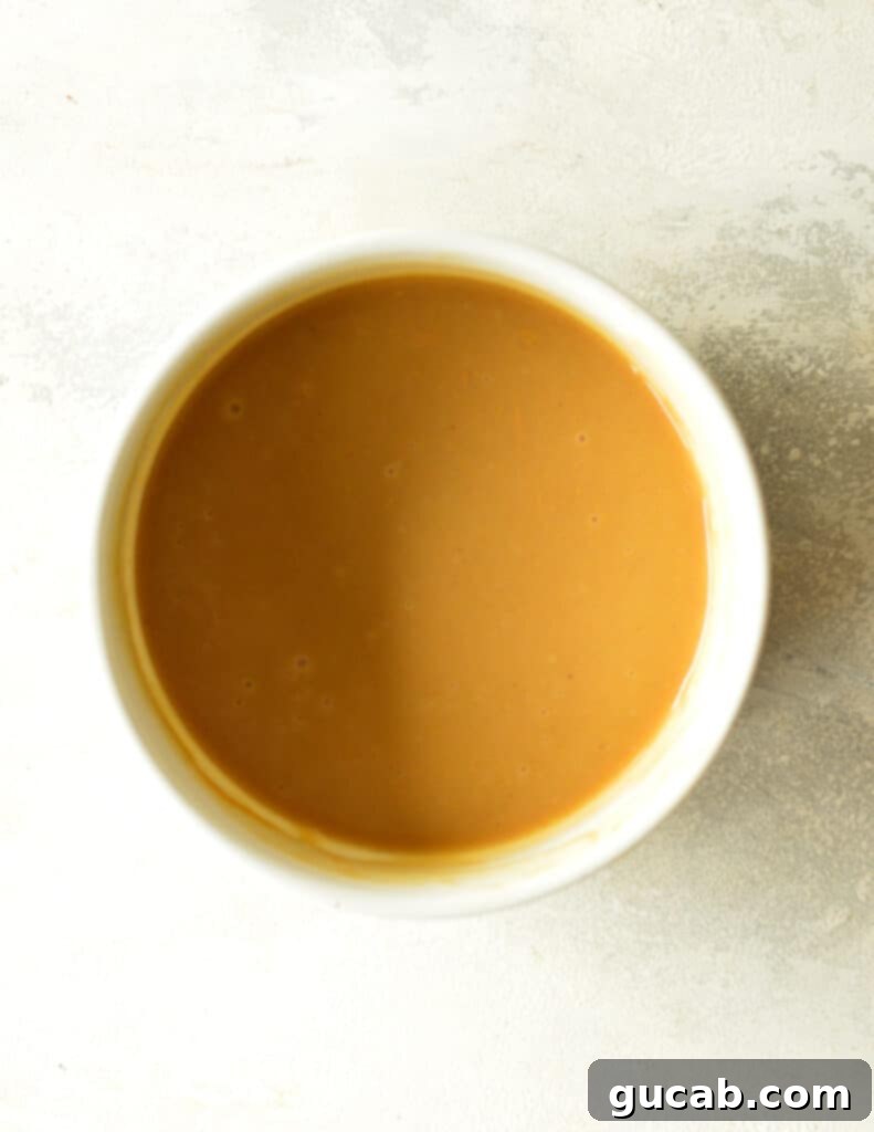 A bowl of freshly stirred peanut butter ganache, looking smooth and pourable, ready to be used or to cool further.