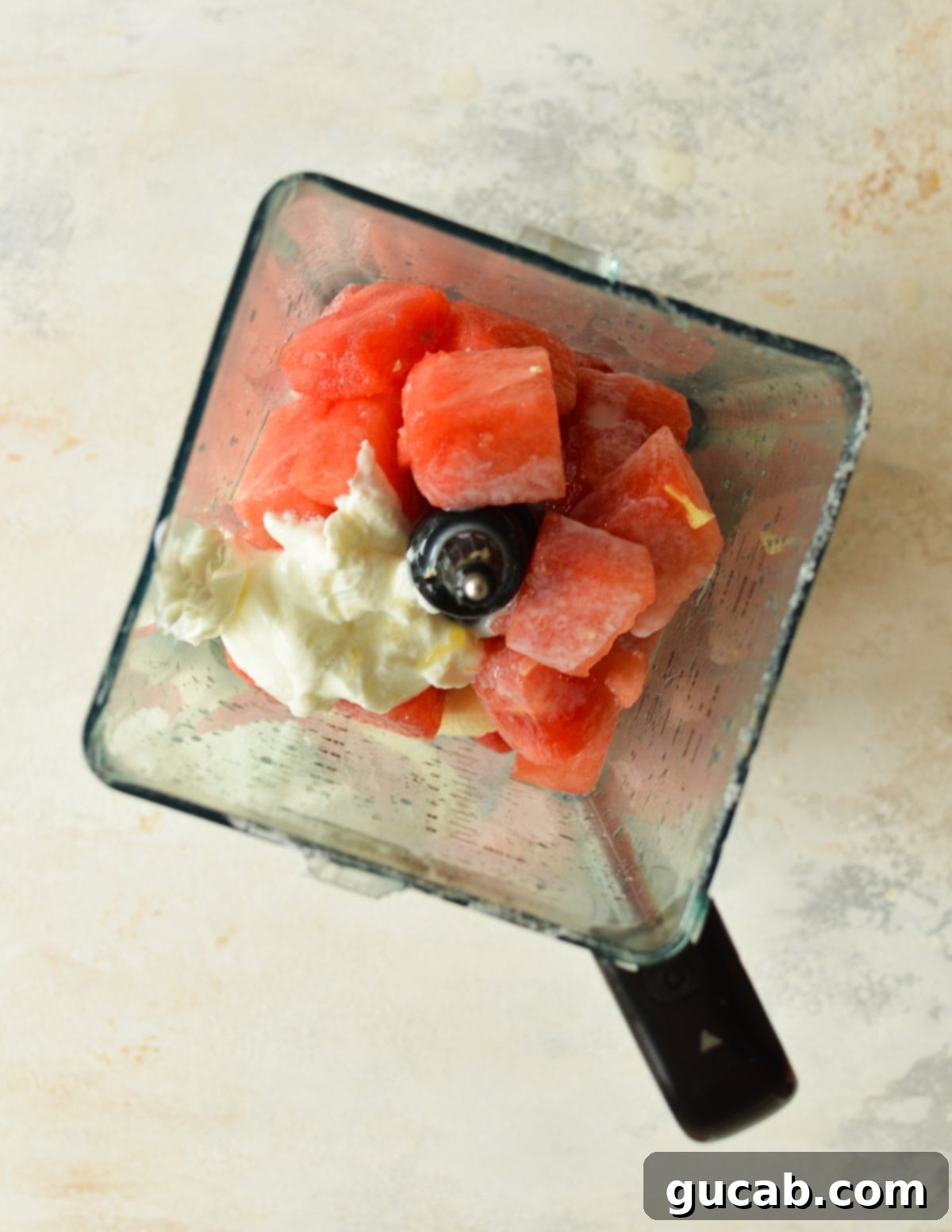 A high-speed blender filled with watermelon chunks, Greek yogurt, and other ingredients, ready for blending.